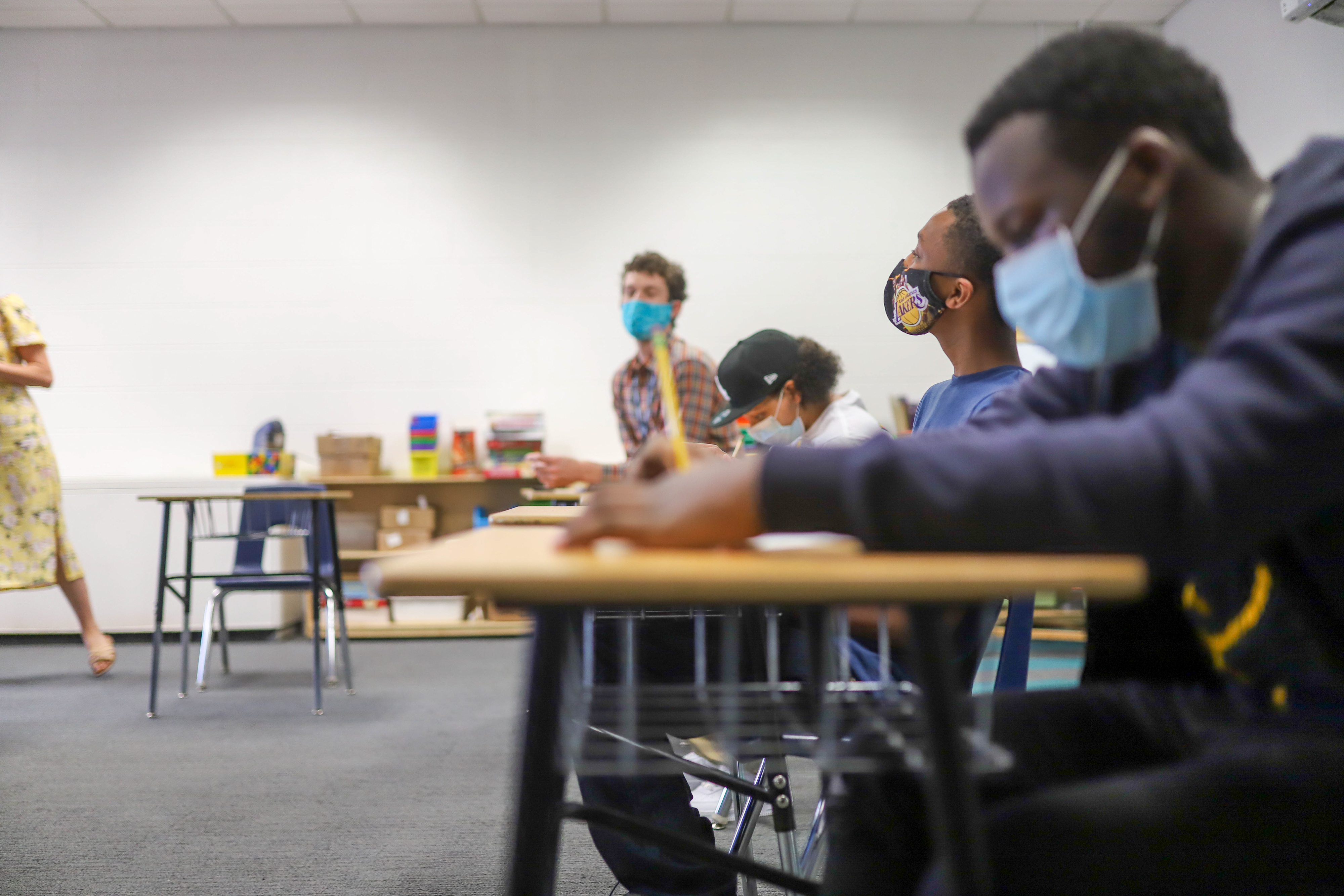 Four students wearing masks work at their desks in a classroom.