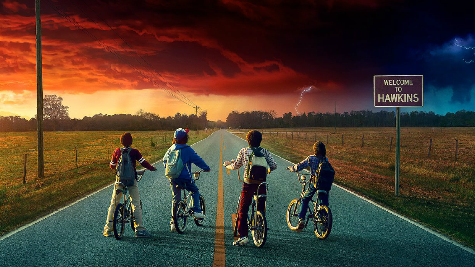 “Stranger Things 2” promo image of four kids on bikes, stopped on a paved road, looking at a threatening cloud on the horizon.