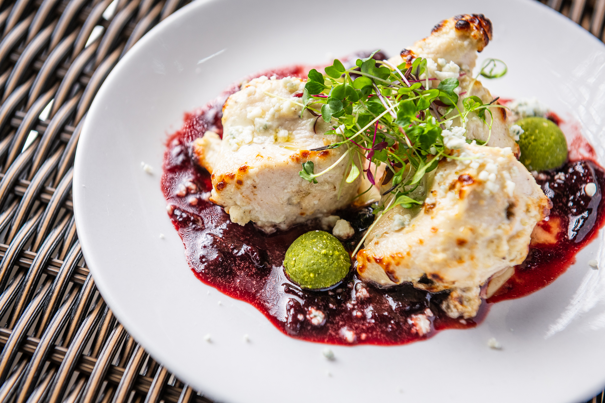 Pieces of chicken from Daru’s reshmi kebab are coated in a yogurt and blue cheese marinade while sitting above a deep red sour cherry sauce and chutney spheres.