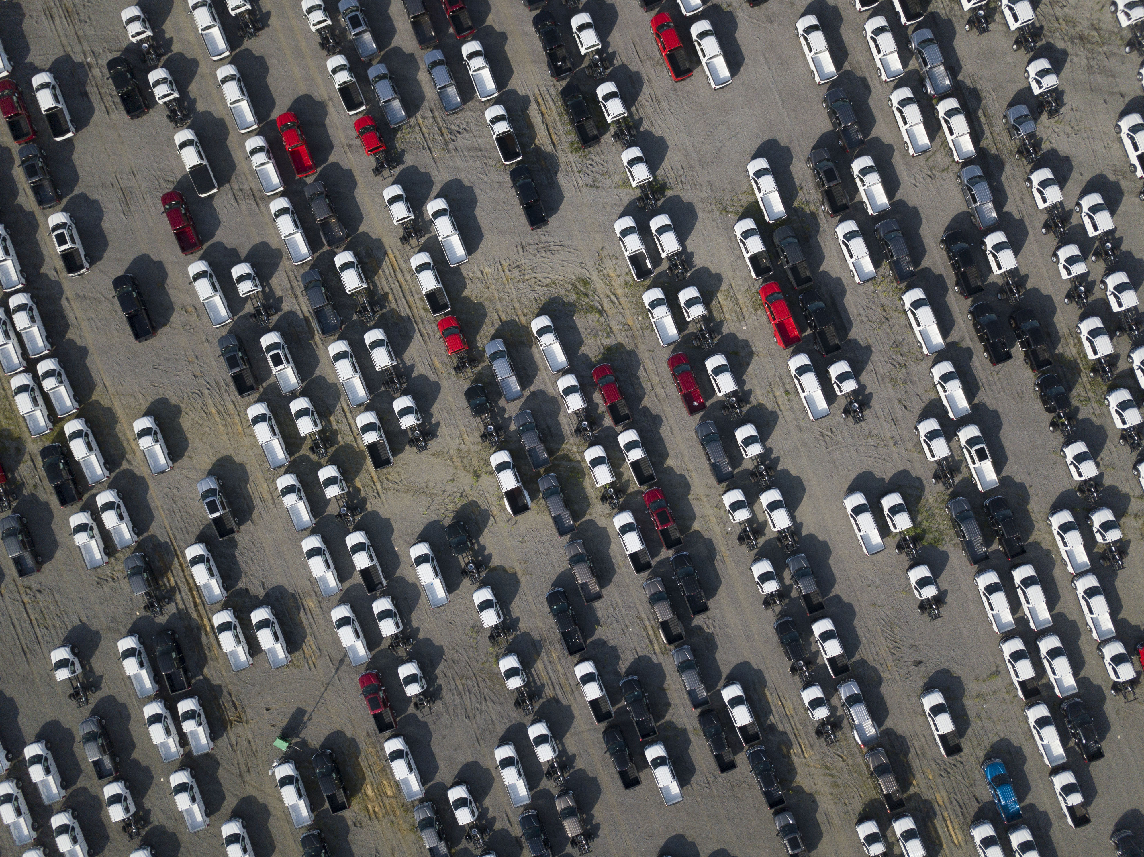 A parking lot with rows of new trucks, seen from high above.