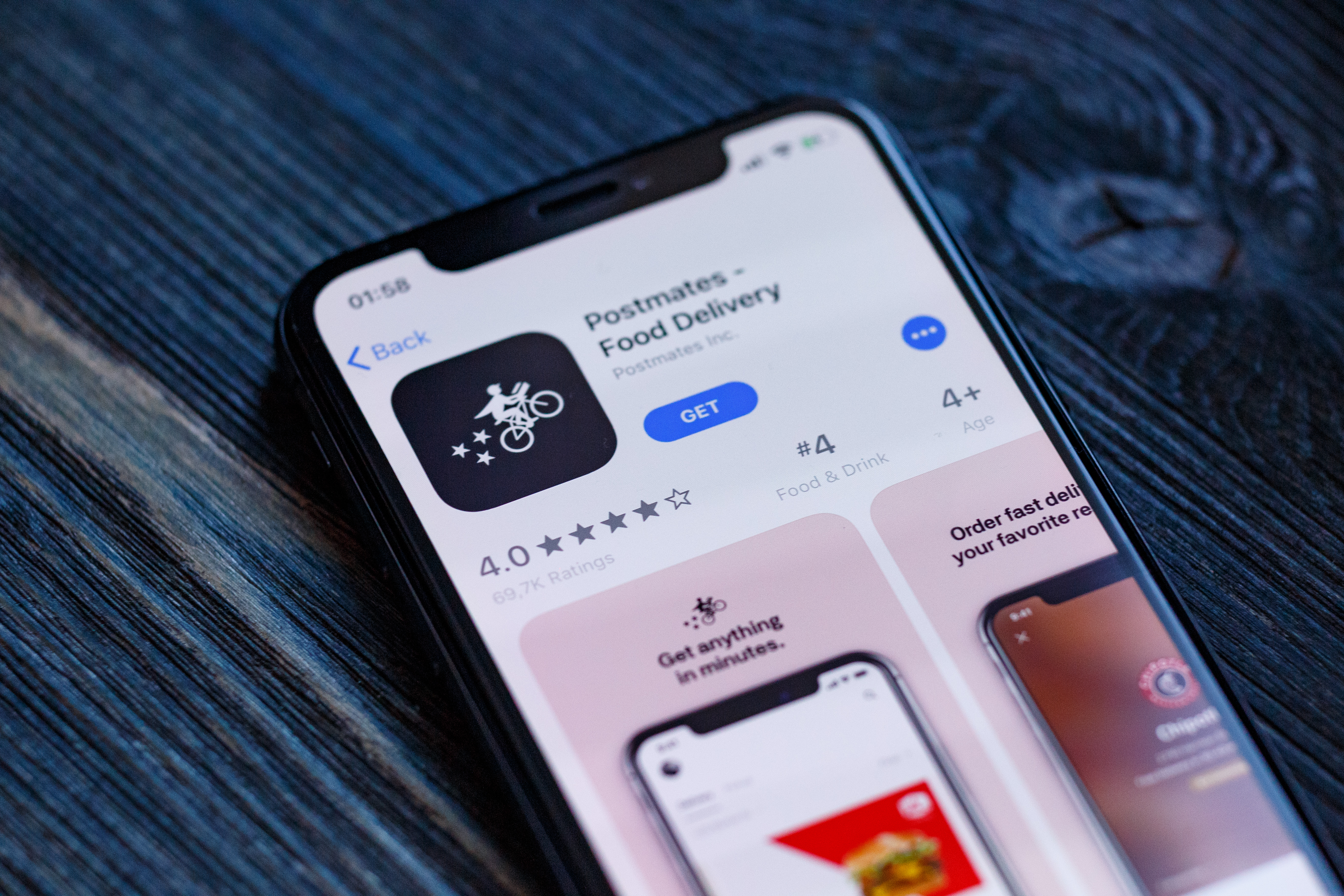 A cell phone displays the Postmates logo in an app store.