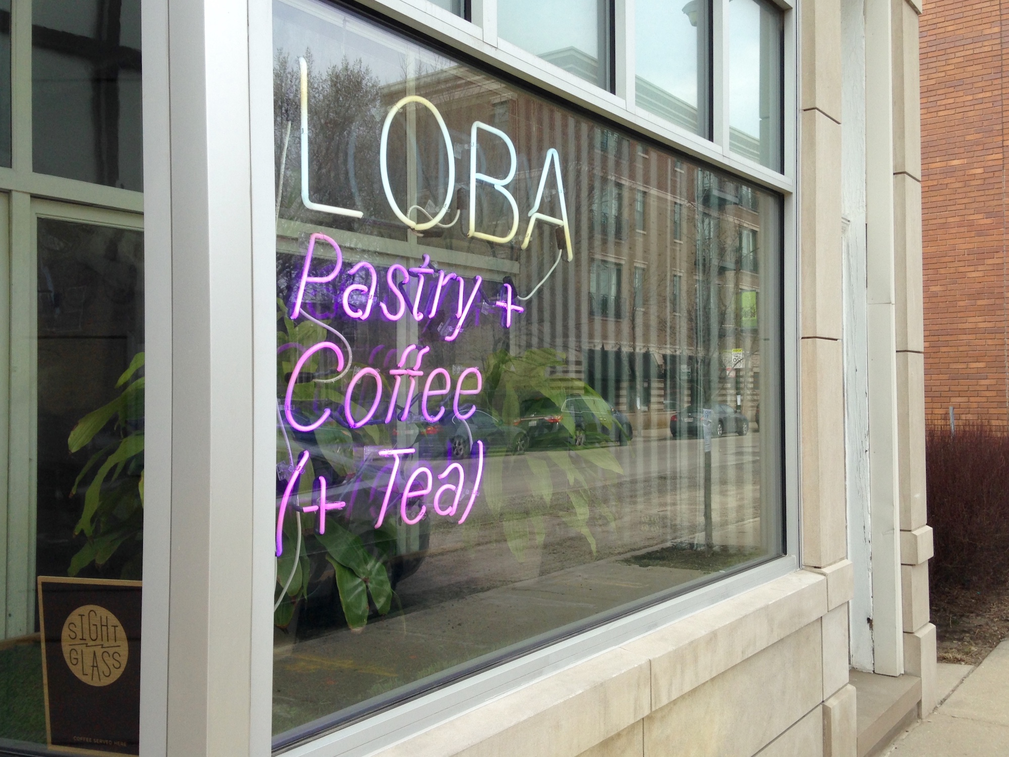 a coffee shop window with neon sign reading “Loba”