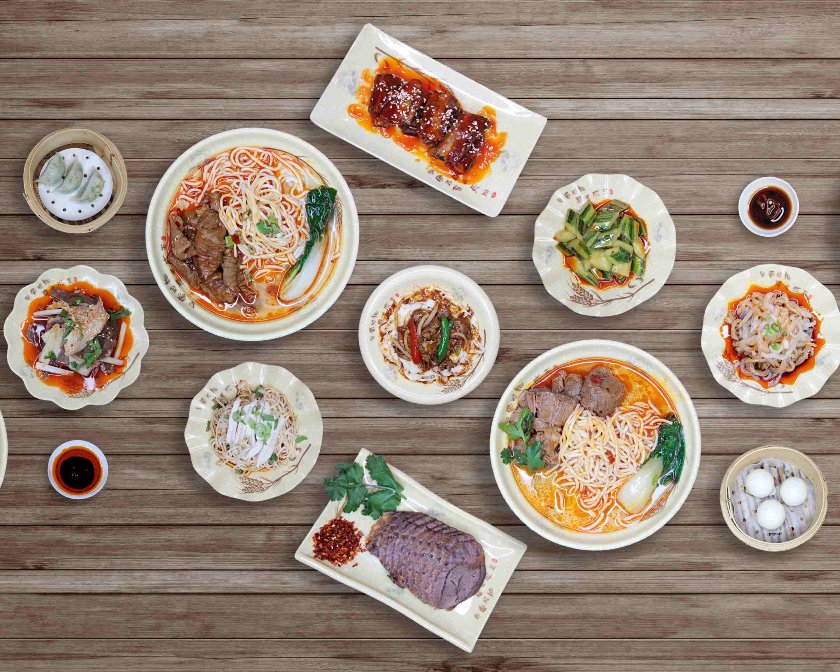 A spread of dishes from Sichuan Popo seen from above, including cold chicken, noodles, greens, and noodle soup