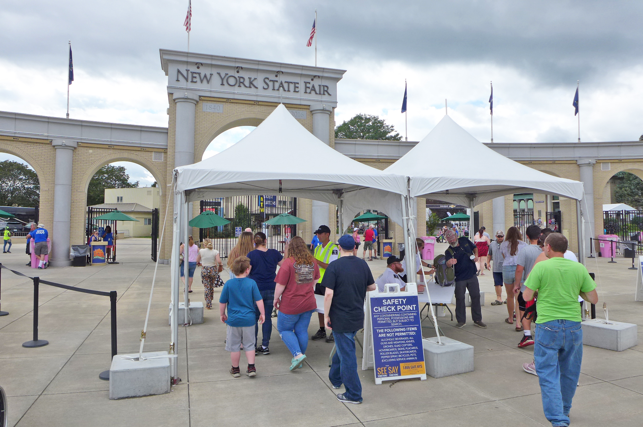 An arch with New York State Fair engraved on it with attendees lined up in front