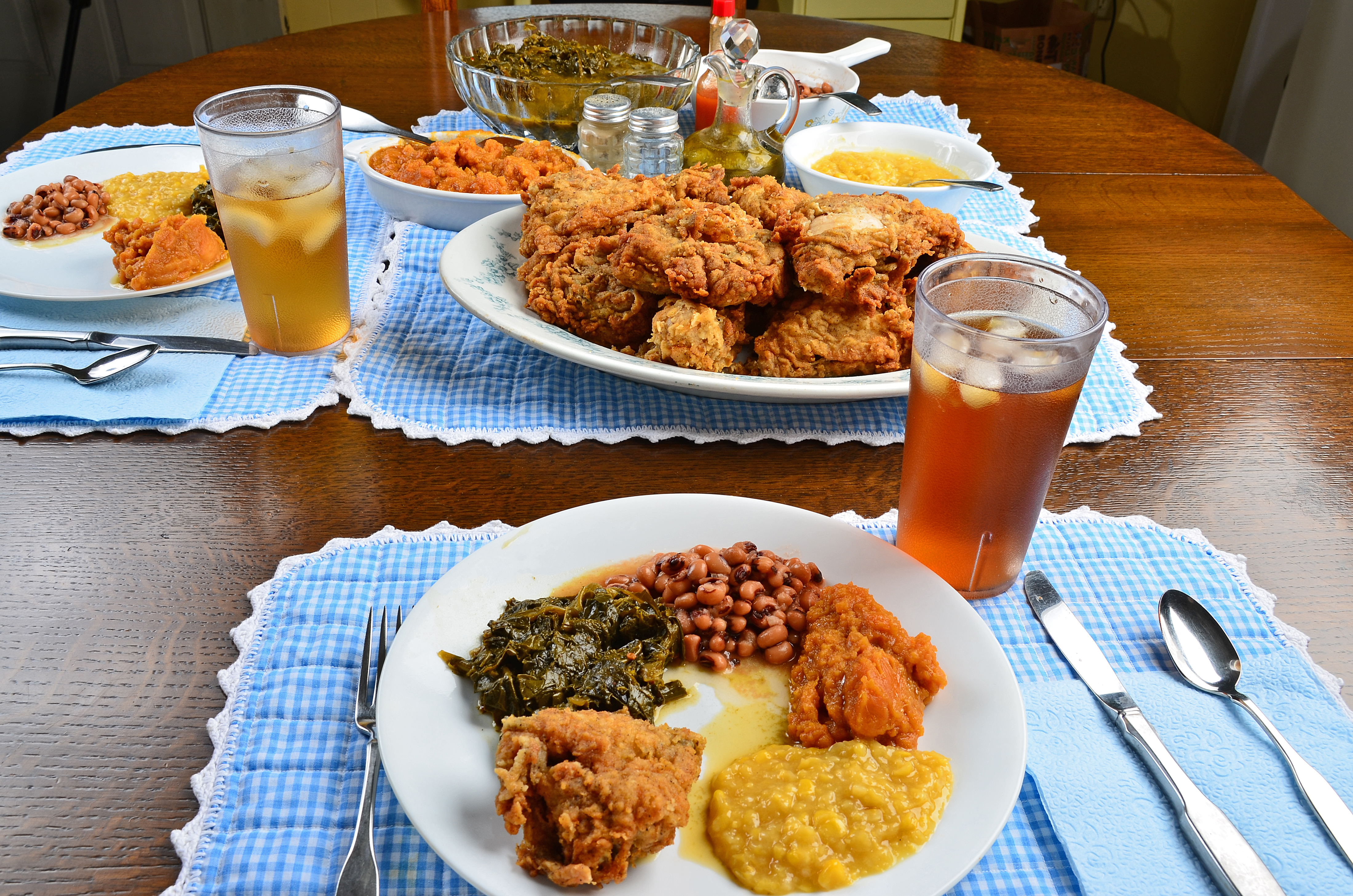 Black-Eyed Pea, Blue Gingham, Candied Yams, Collard Greens, Corn, Dinner, Dishware, Drink, Eating, Family Dinner, Family Style, Food, Fork, Fried Chicken, Ice Tea, Latin American Cuisine, Place Mat, Plate, Silverware, Spoon, Sweet Potato, Table, Table Knife, Wide-Angle Lens.