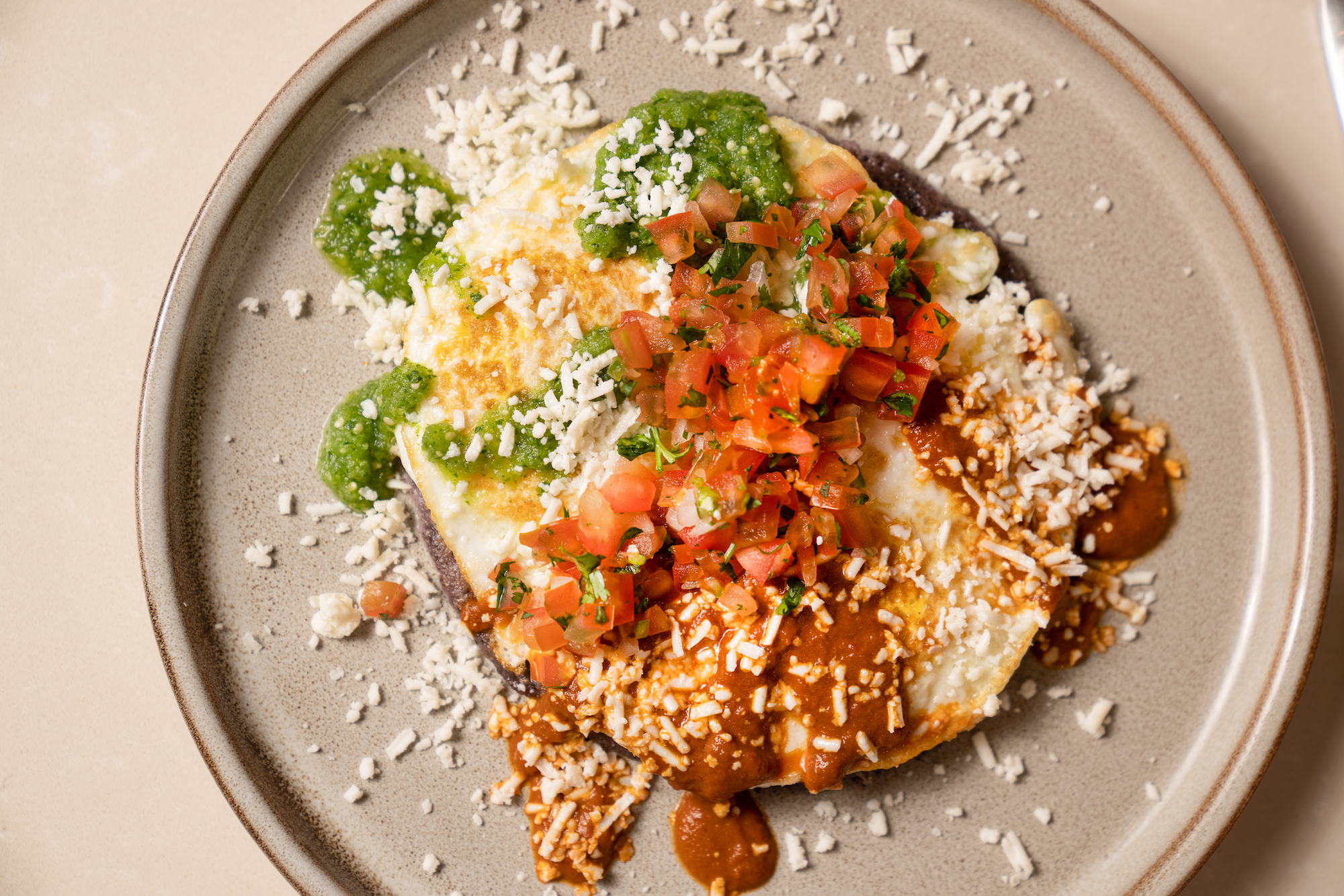 A chilaquiles with cheese on a tan plate