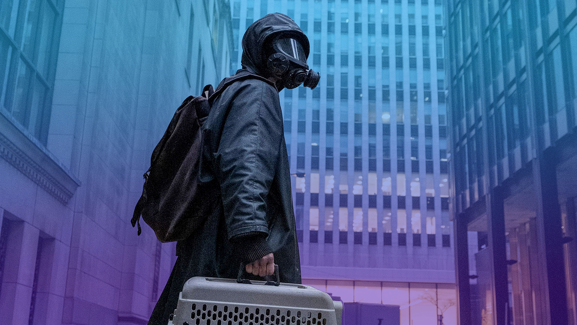 Photo of Yorick Brown (Ben Schnetzer) wearing a waterproof coat and wearing a gas mask stands atop a car carrying an animal crate