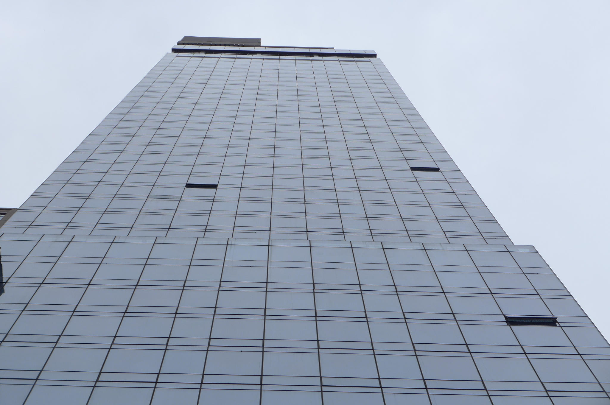 A tall, dark-windowed building stands against a gray sky