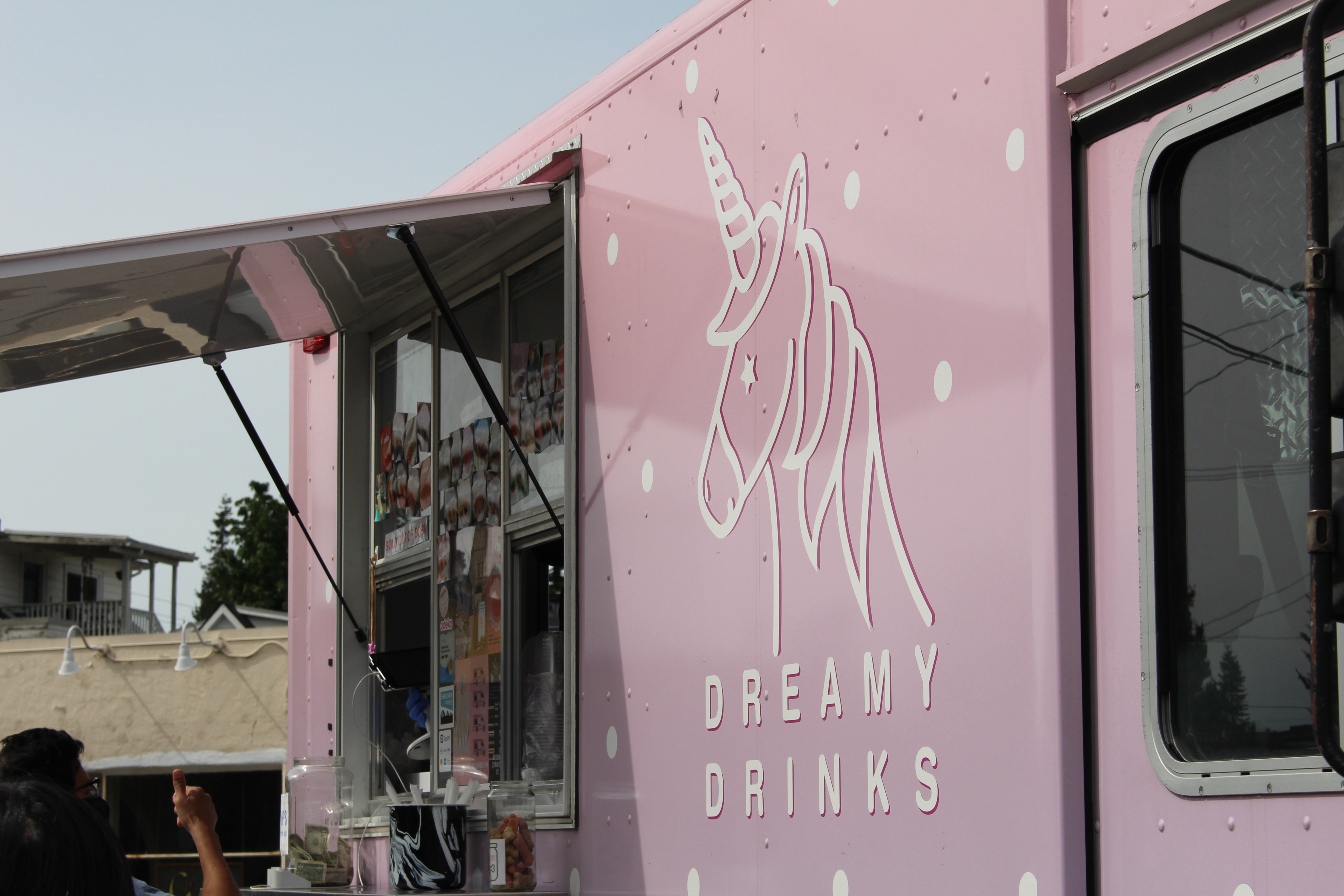 The pink facade of the Dreamy Drinks boba tea/food truck, with the business’s name on the front underneath a logo of a unicorn traced in white.