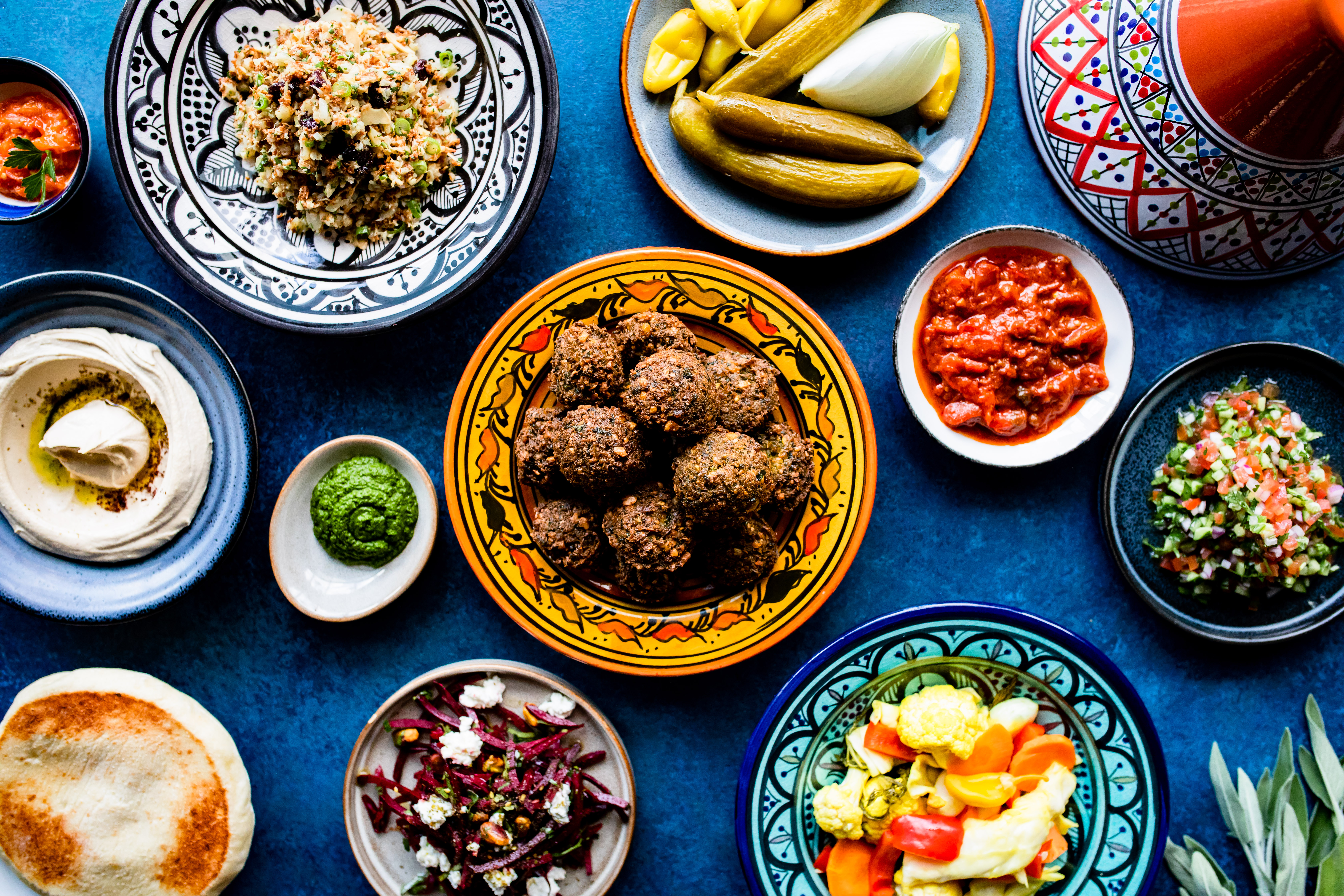 Plates of falafel, salatim, hummus, sauces, pita bread, and more at Hamsa.