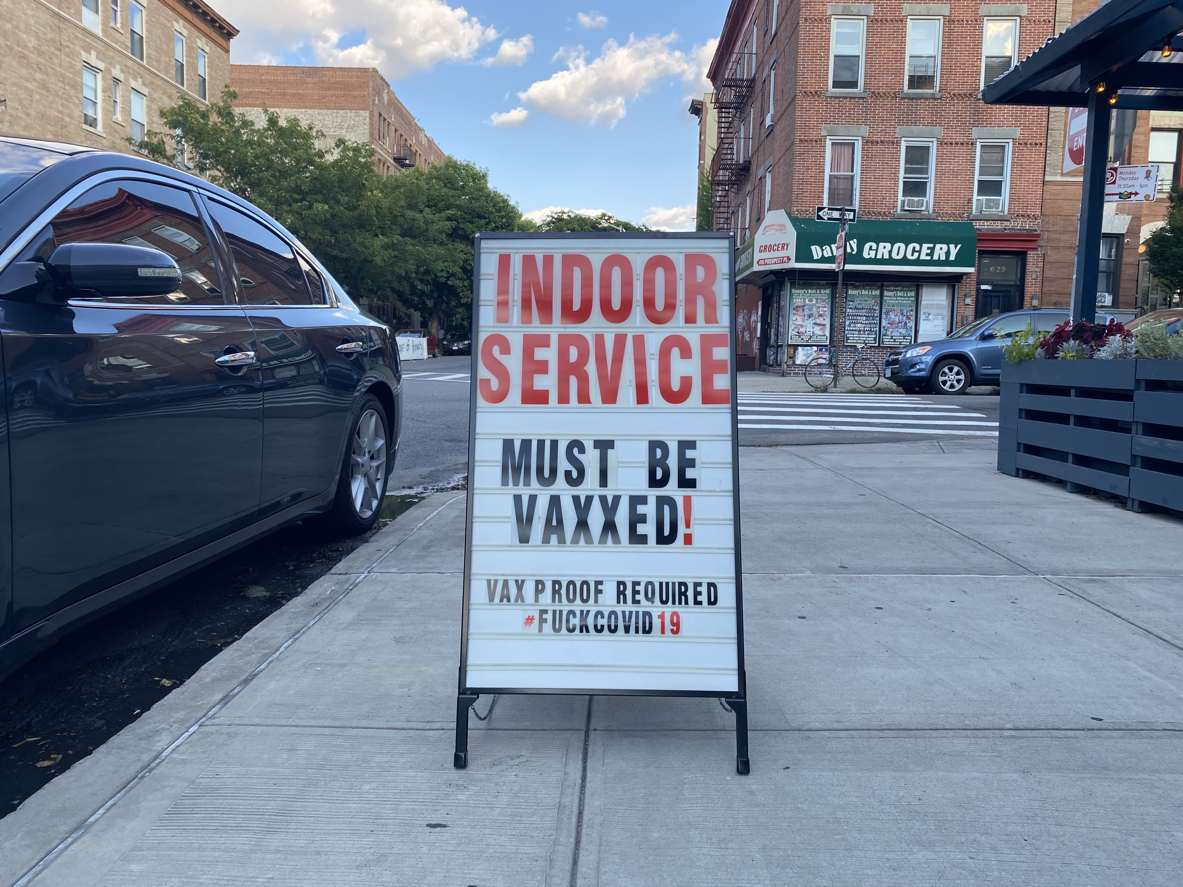 A sandwich board sign with the words “Indoor service must be vaxxed! Vax proof required #fuckcovid19”