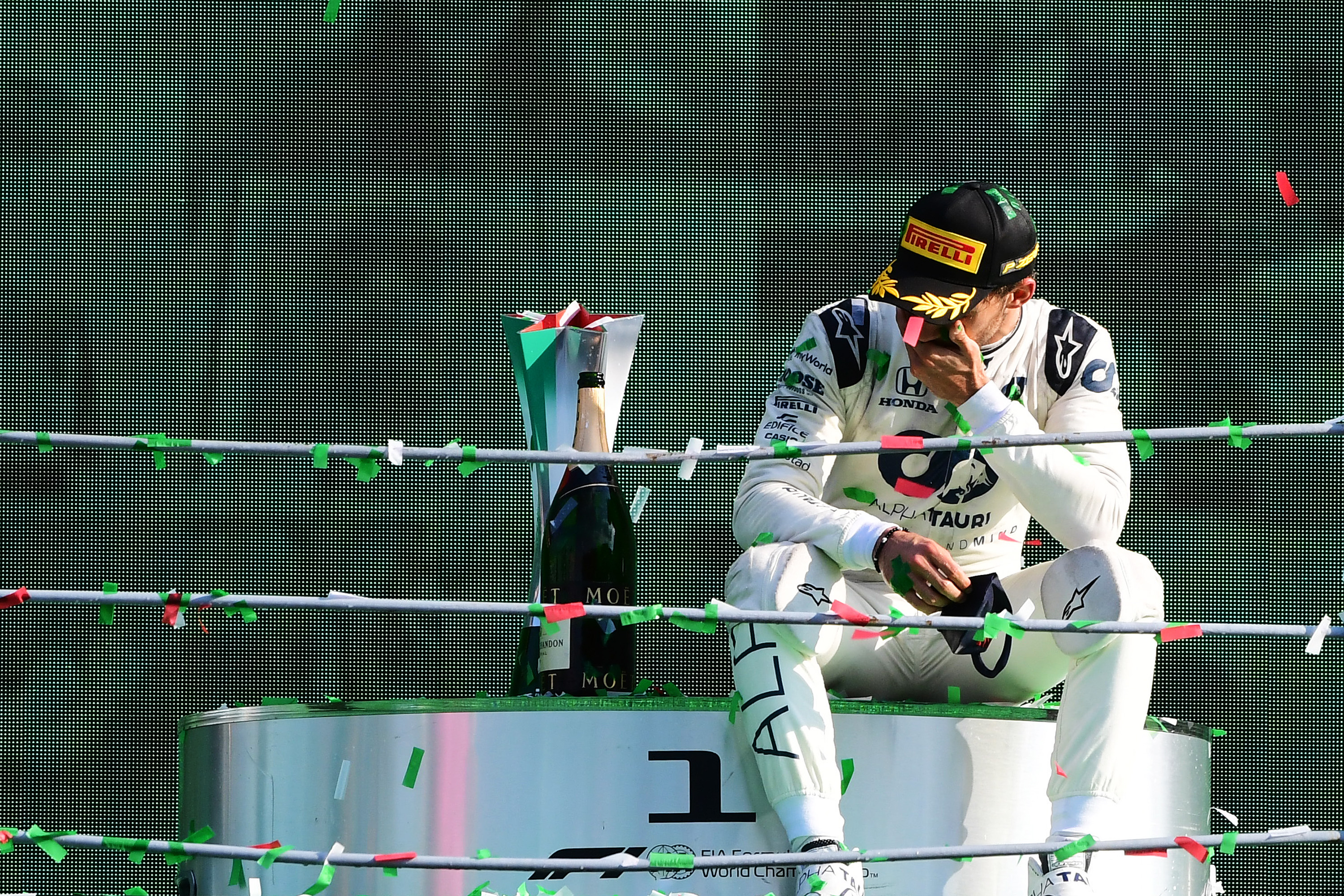 Race car driver Pierre Gasly sits on the winner’s dais beside a bottle of champagne after the F1 Grand Prix.