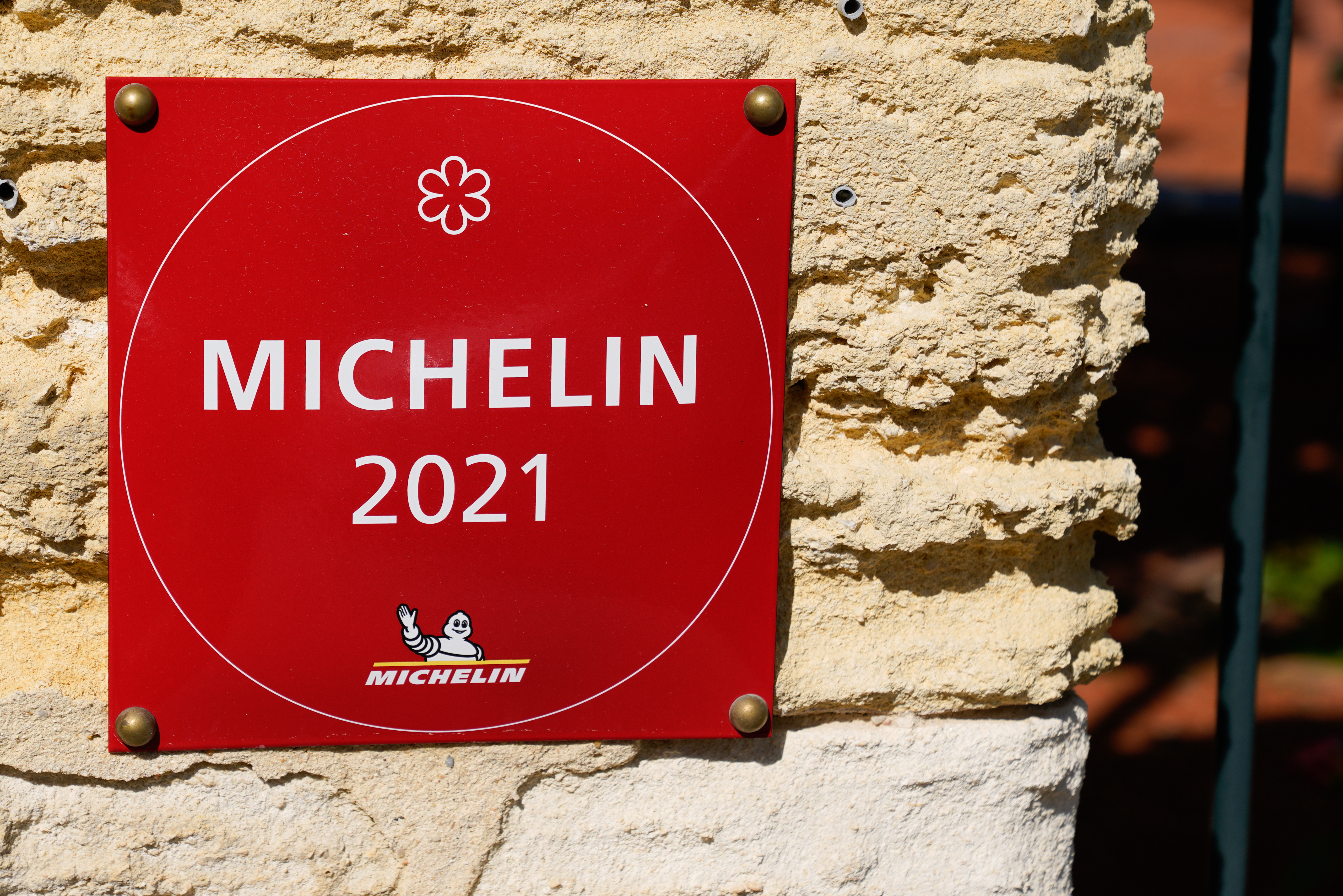 A red Michelin Guide 2021 sign is affixed to a stone wall.