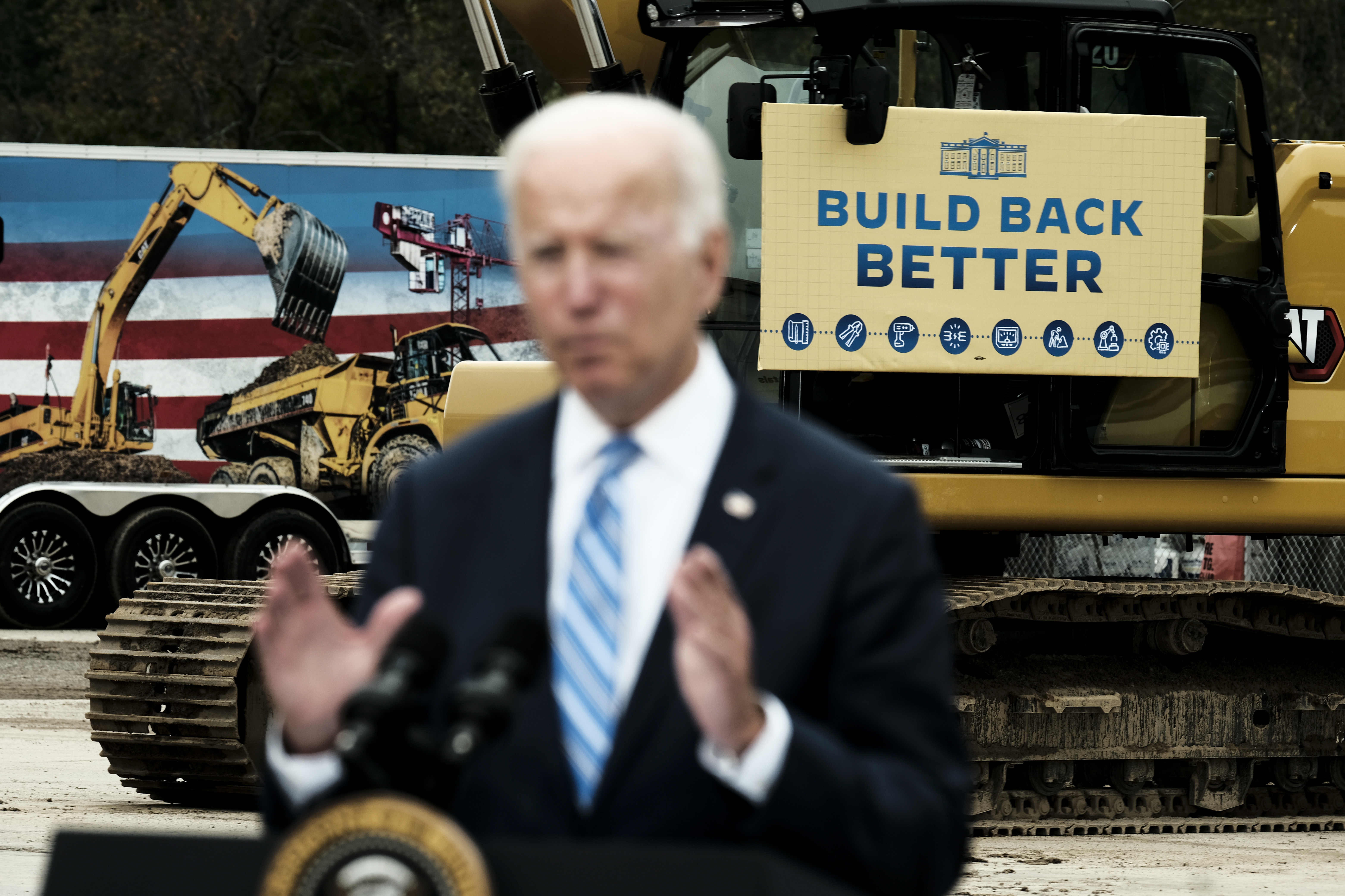 President Joe Biden speaking in front of construction equipment bearing a “build back better” sign.