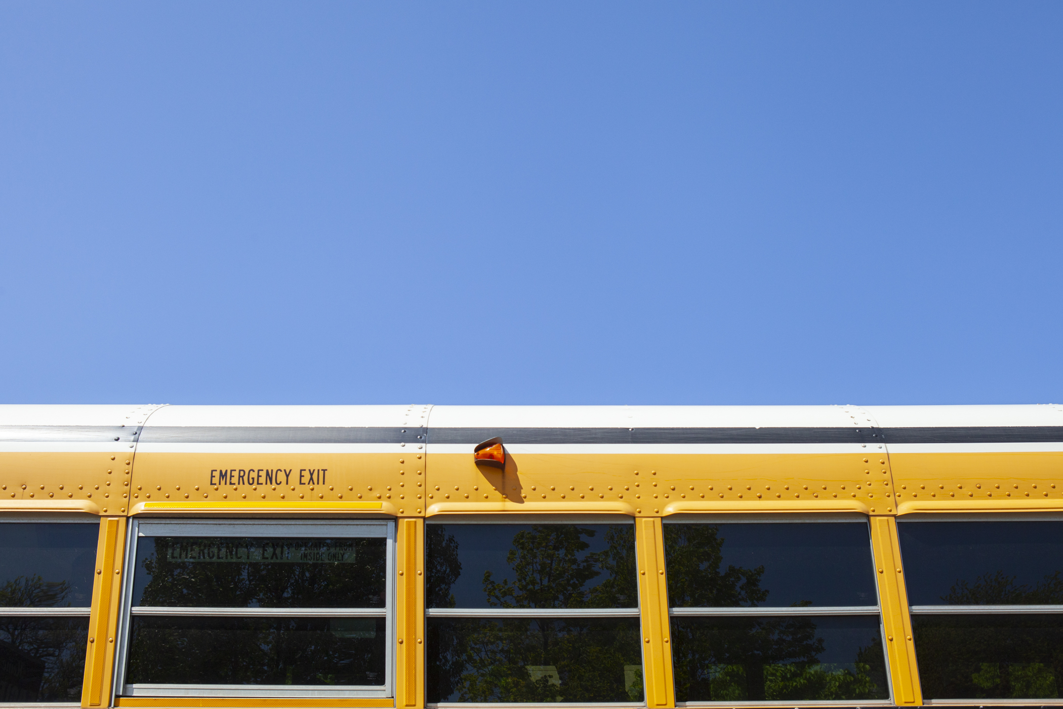 The top of a school bus splits is pictured against a bright blue sky.
