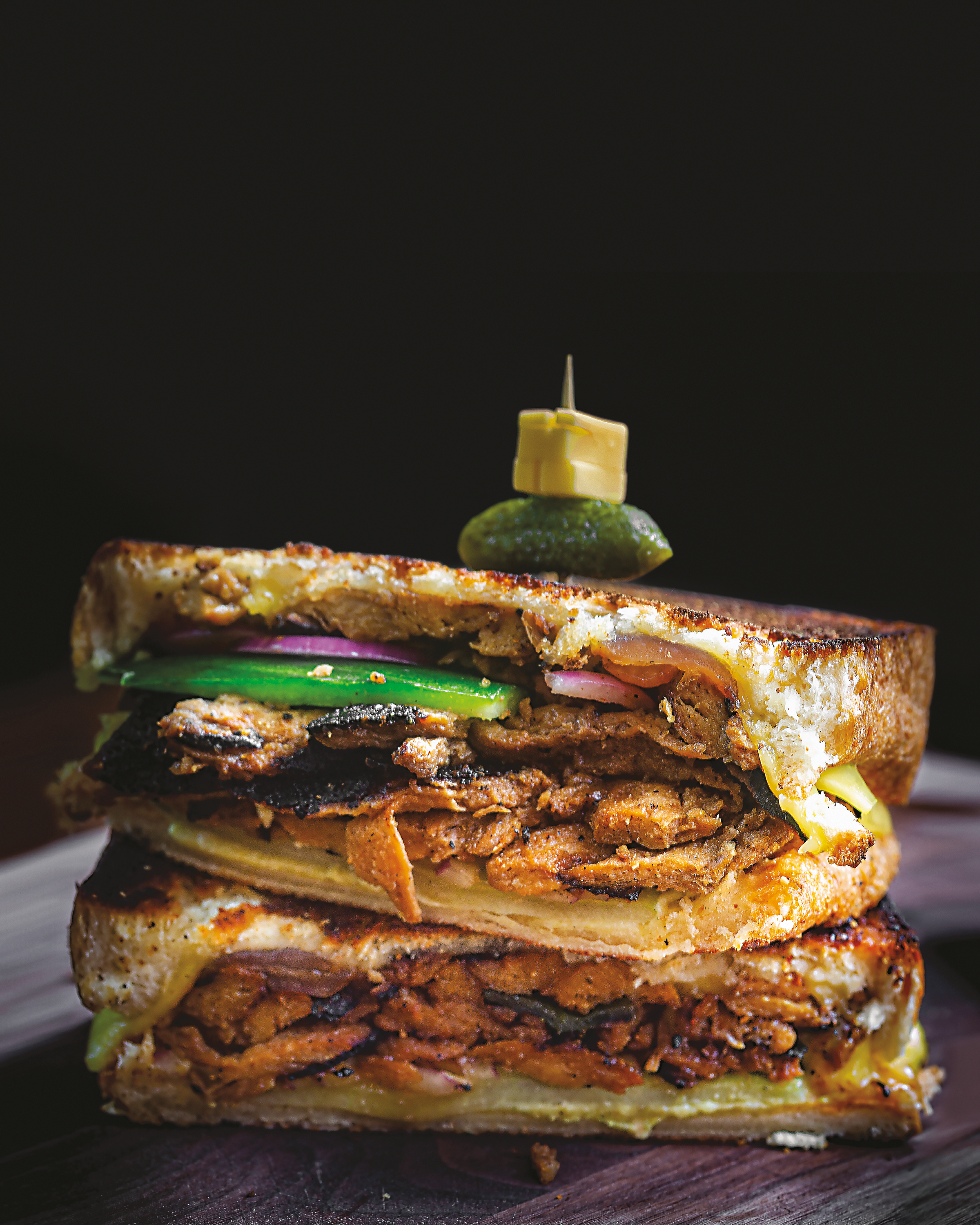 A toasted sandwich sliced in half so you can see the interior, filled with green pepper, onion, and bulgogi
