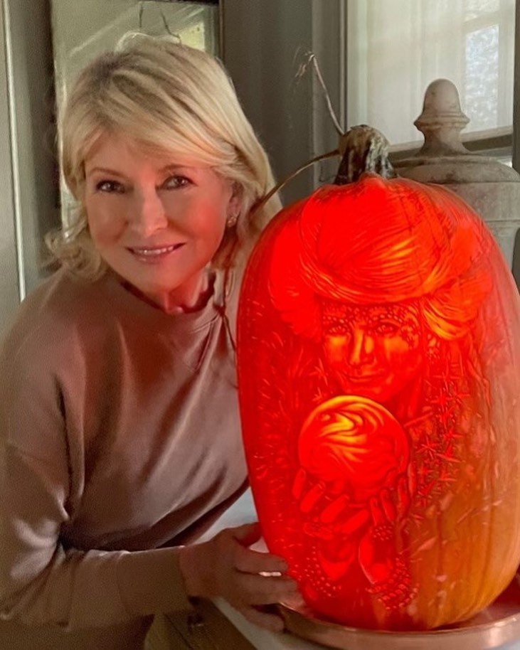 A photo of Martha Stewart posing next to a carved pumpkin, etched with a photo of her dressed as a witch.