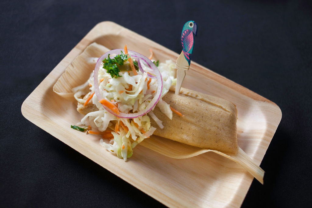 A tamalito on a plate topped with a vegetable slaw.