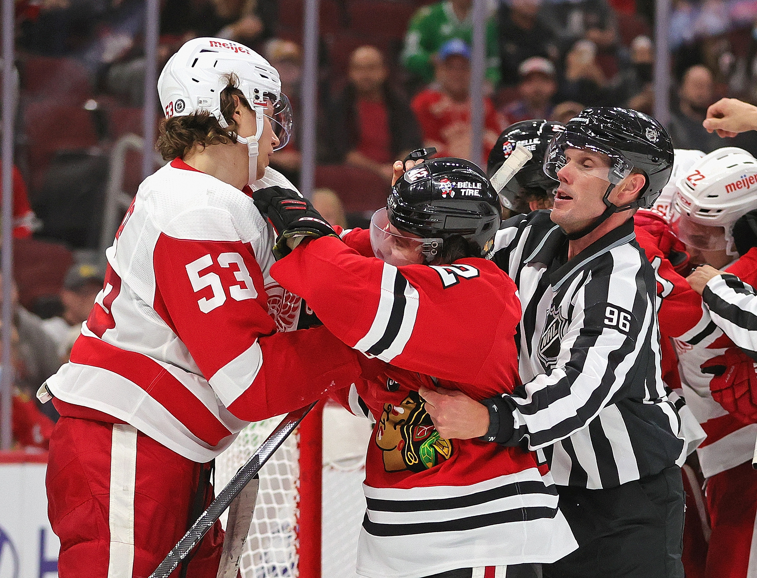 Linesman David Brisebois #96 tries to break up an altercation between Alex DeBrincat #12 of the Chicago Blackhawks and Moritz Seider #53 of the Detroit Red Wings at the United Center on October 24, 2021 in Chicago, Illinois.