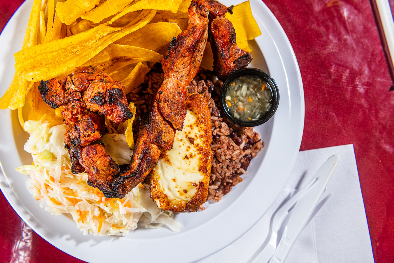 A plate from Eda’s contains well-charred strips of grilled pork, thin ribbons of fried yellow plantain, caramelized blocks of fried cheese, and a dark mix of rice and red beans.