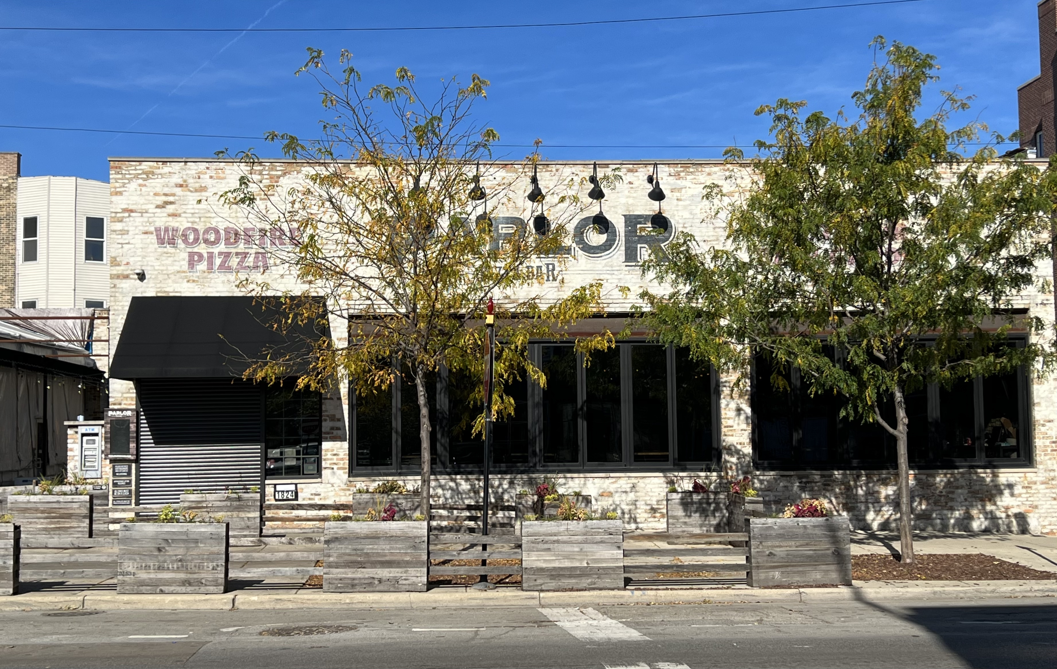 A brick exterior of a restaurant with two trees in the fall.