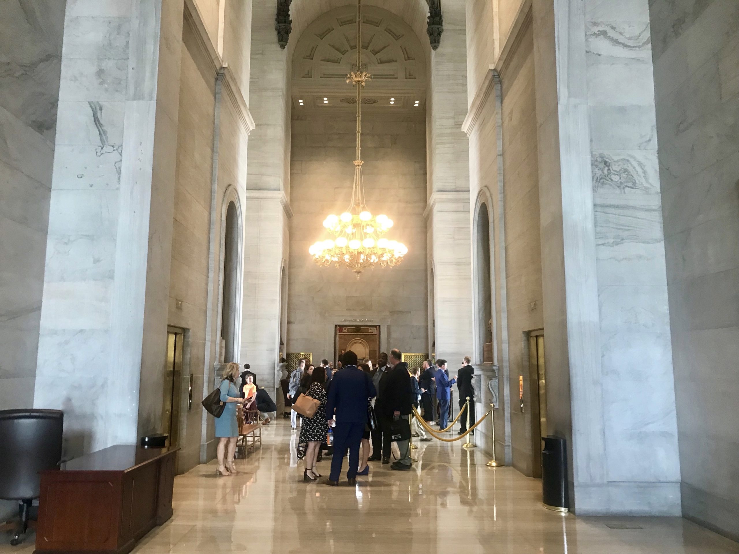 People flanked by tall pillars stand in the Tennessee State Capitol rotunda.