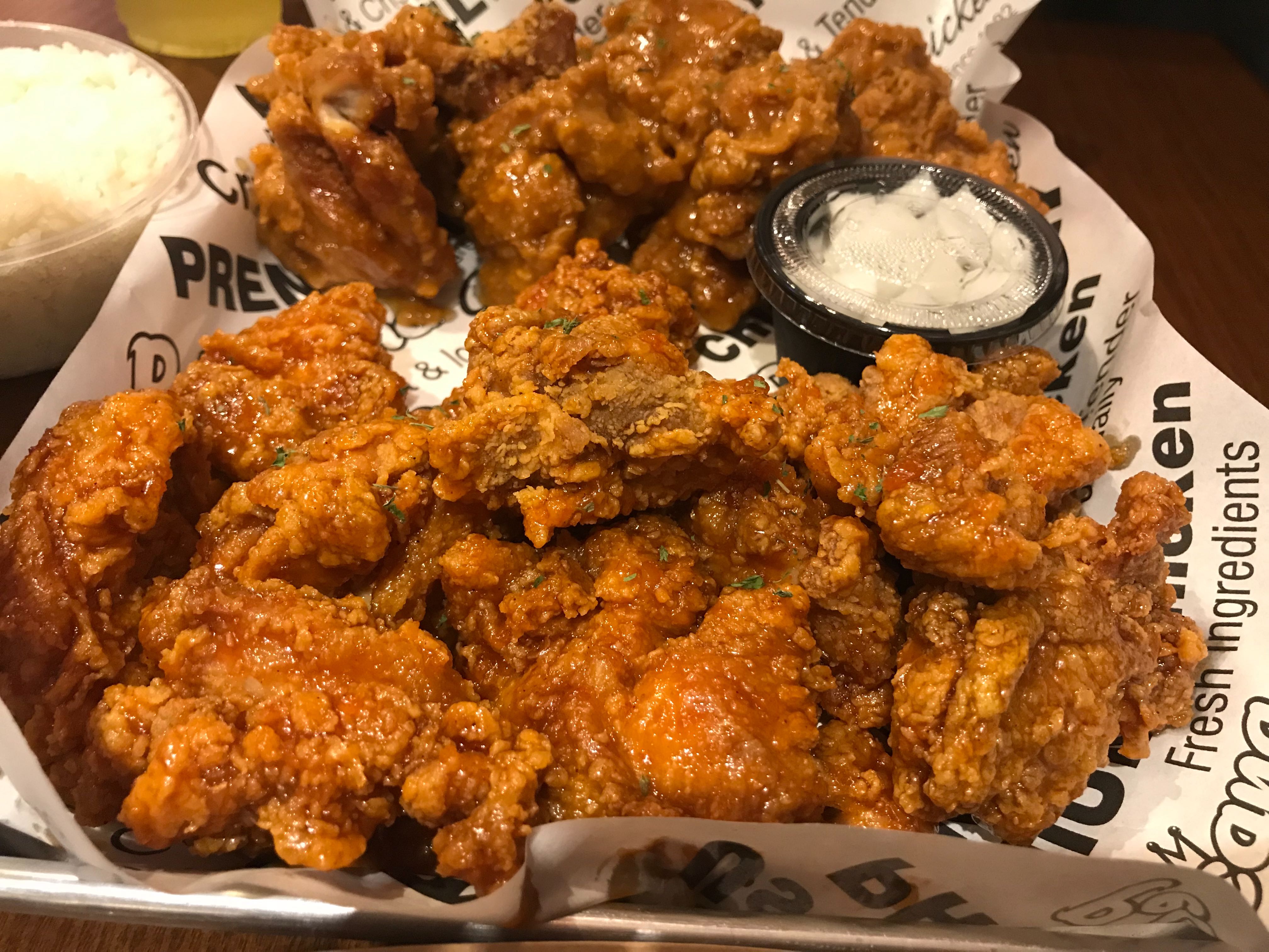 A plate of fried chicken wings with ramekin of white dipping sauce.