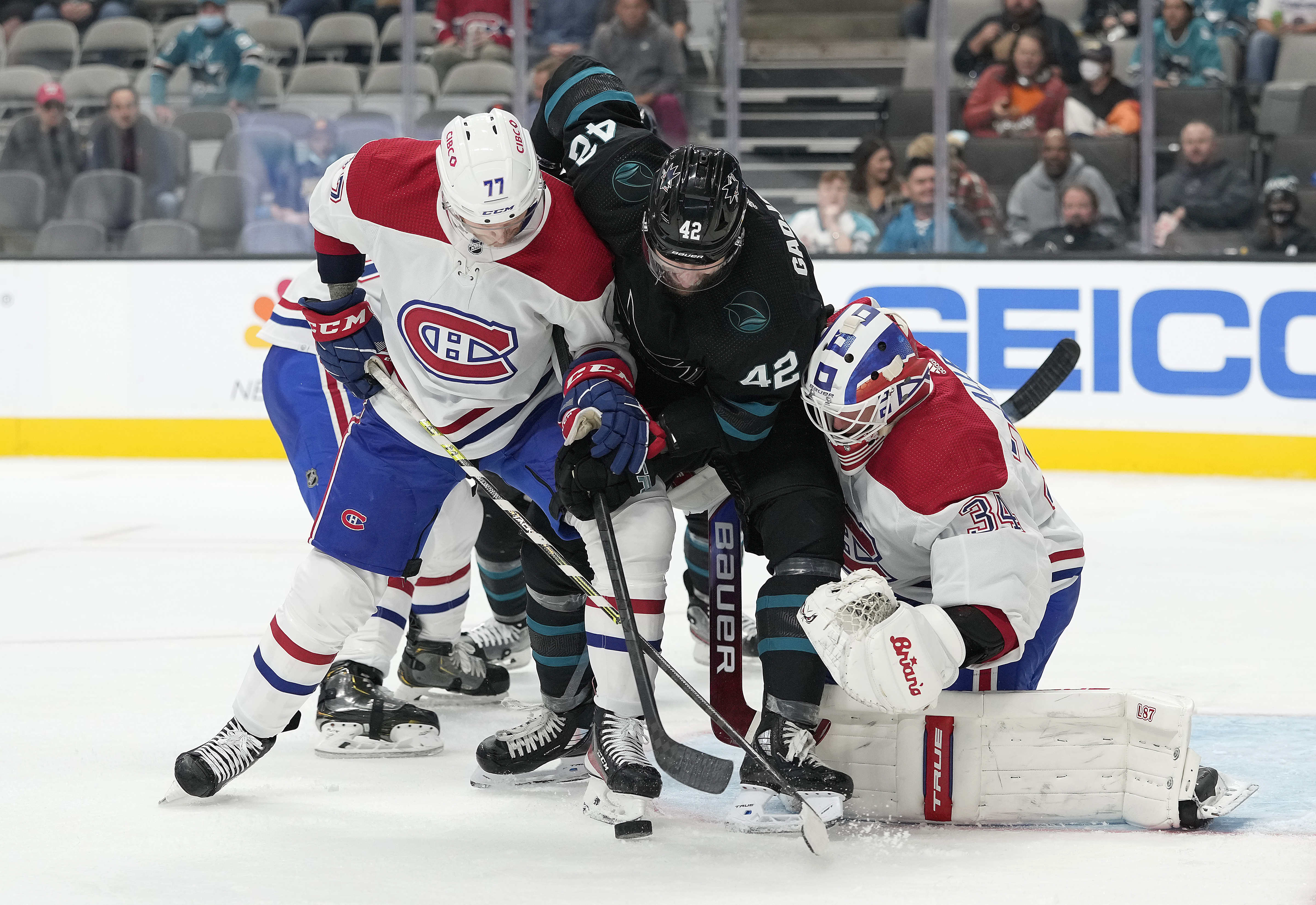 Jonah Gadjovich #42 of the San Jose Sharks battles for control of the puck with Brett Kulak #77 and Jake Allen #34 of the Montreal Canadiens during the second period at SAP Center on October 28, 2021 in San Jose, California.