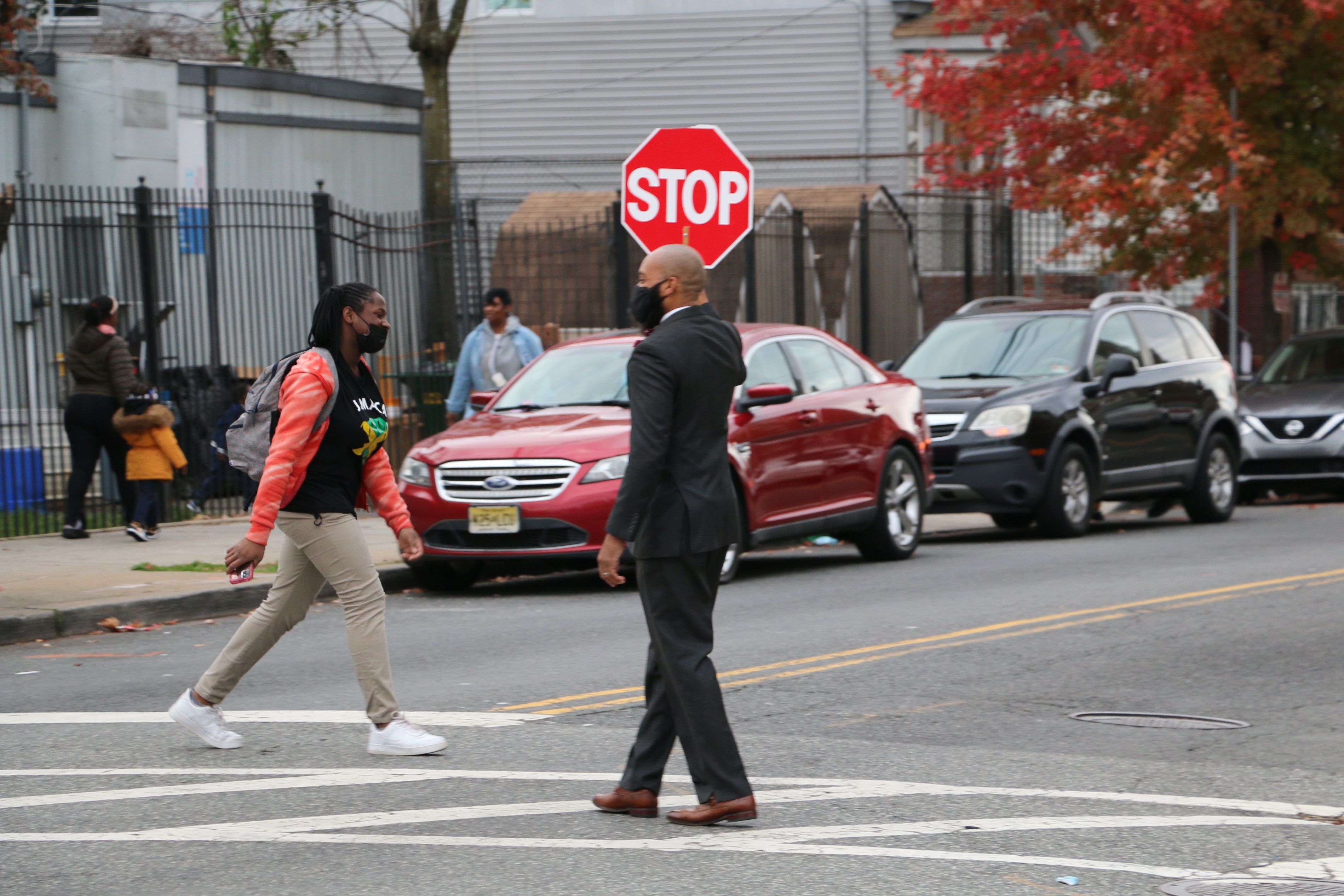 H. Grady James, IV, principal of Hawthorne Avenue School in Newark, stands in a crosswalk and holds a red stop sign as he directs traffic.