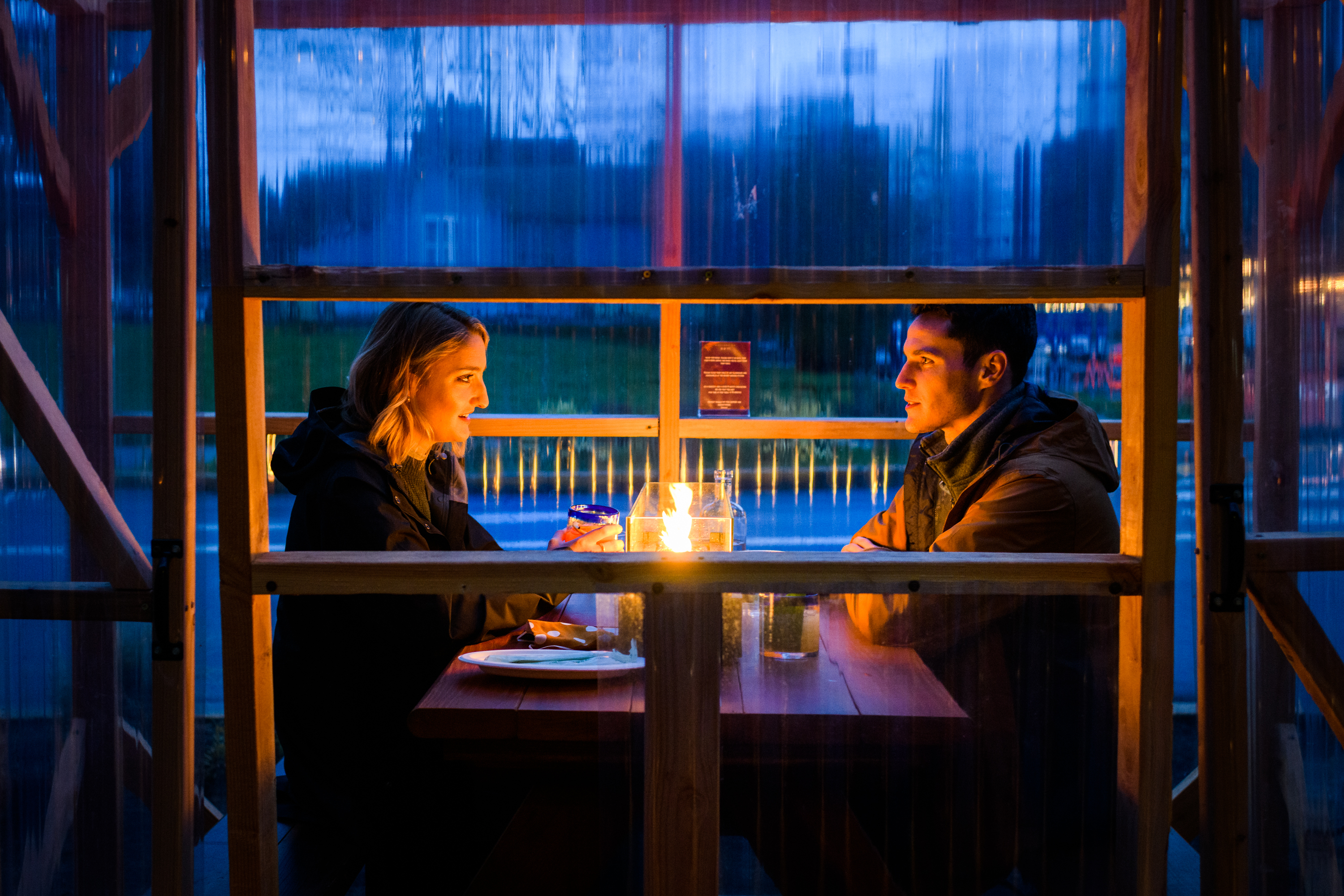 一对夫妇坐在艾姆温室风格的一个小户外桌子的两侧，单方用餐小屋。