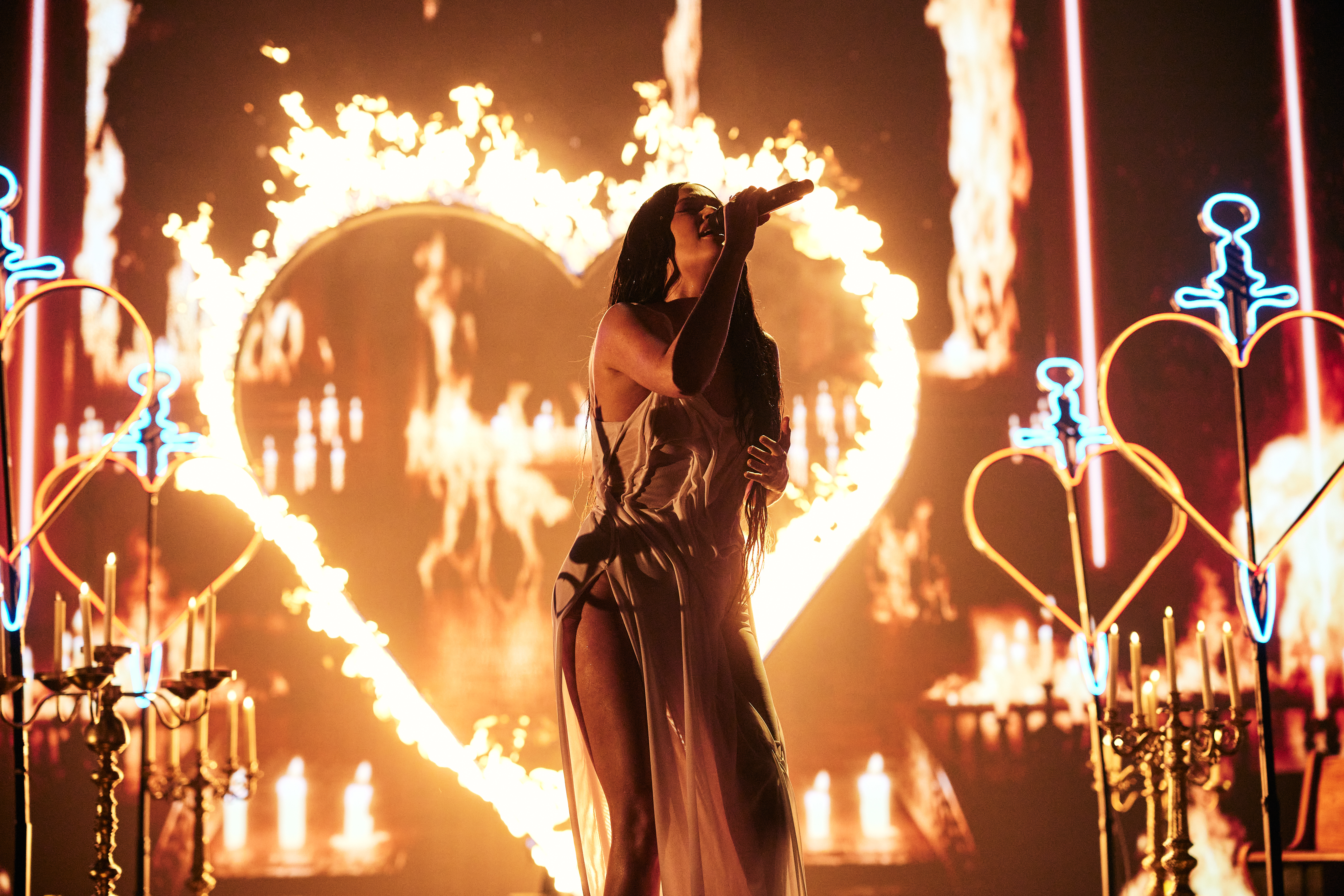 Singer Kacey Musgraves performs onstage at the 2021 MTV Video Music Awards in front of a heart shape outlined by fire.
