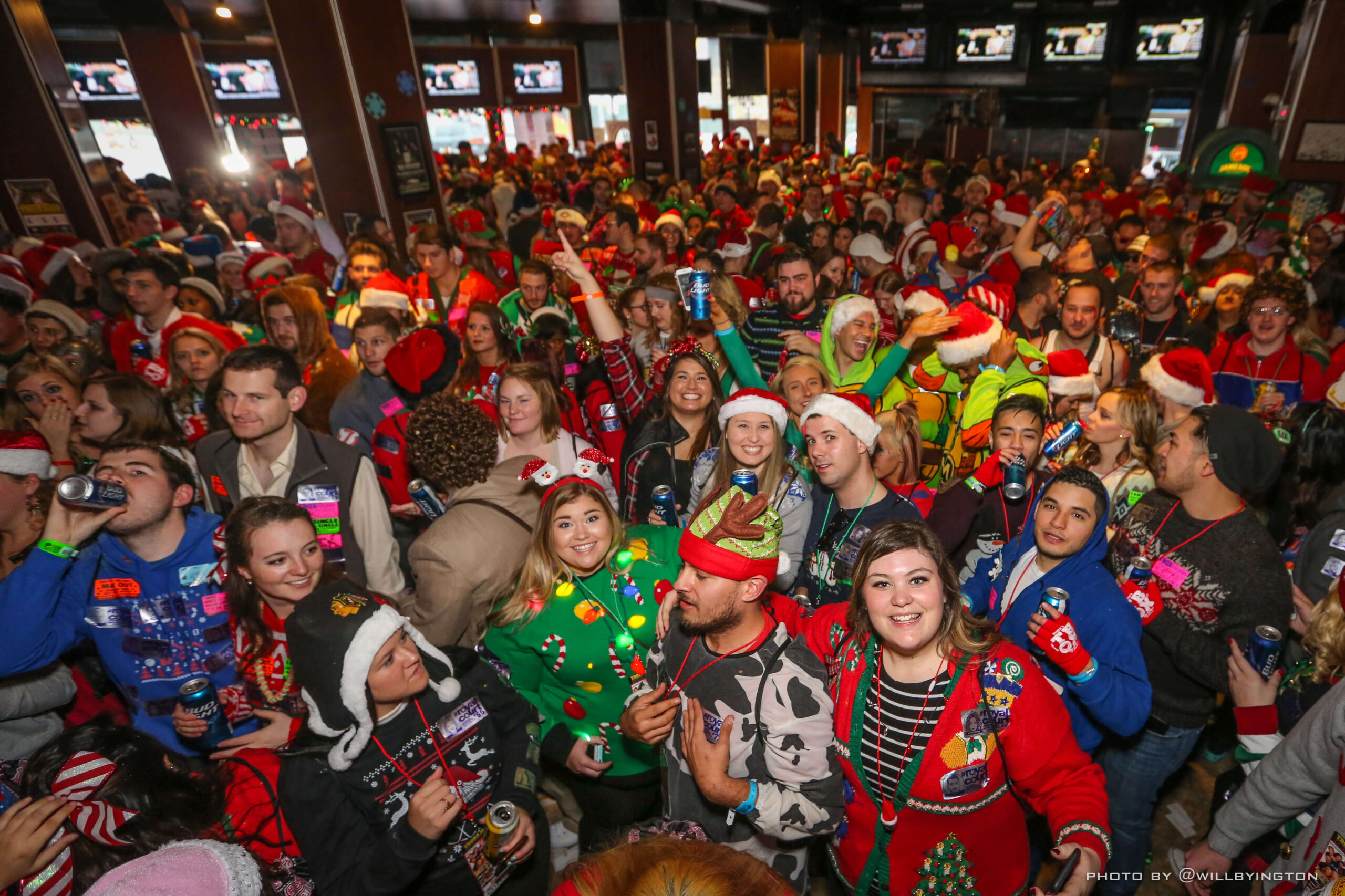 A huge room crowded with hundreds of people in red and green Christmas gear.