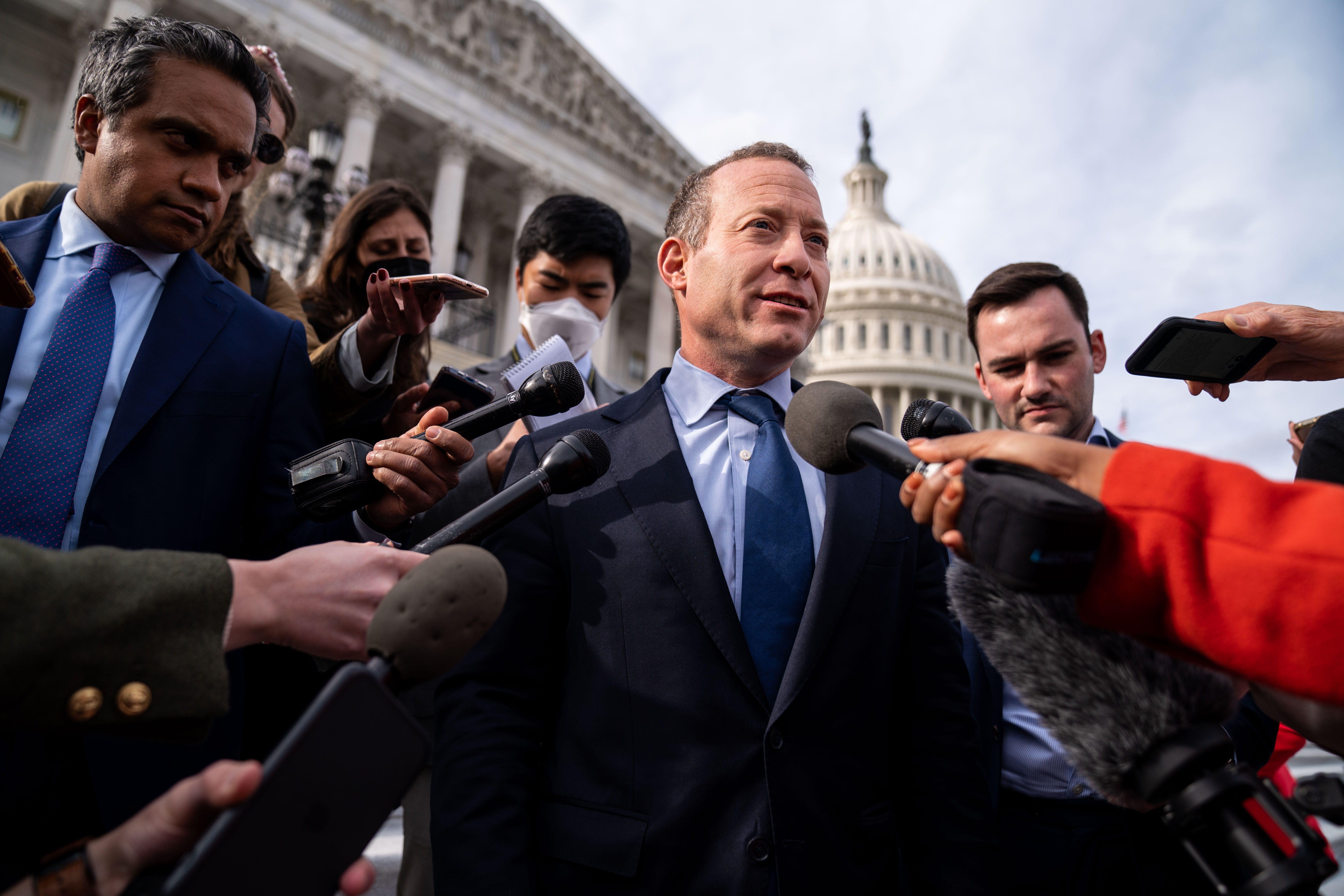 Reporters with mics surround Representtive Josh Gottheimer as the Capitol dome looms in the background.