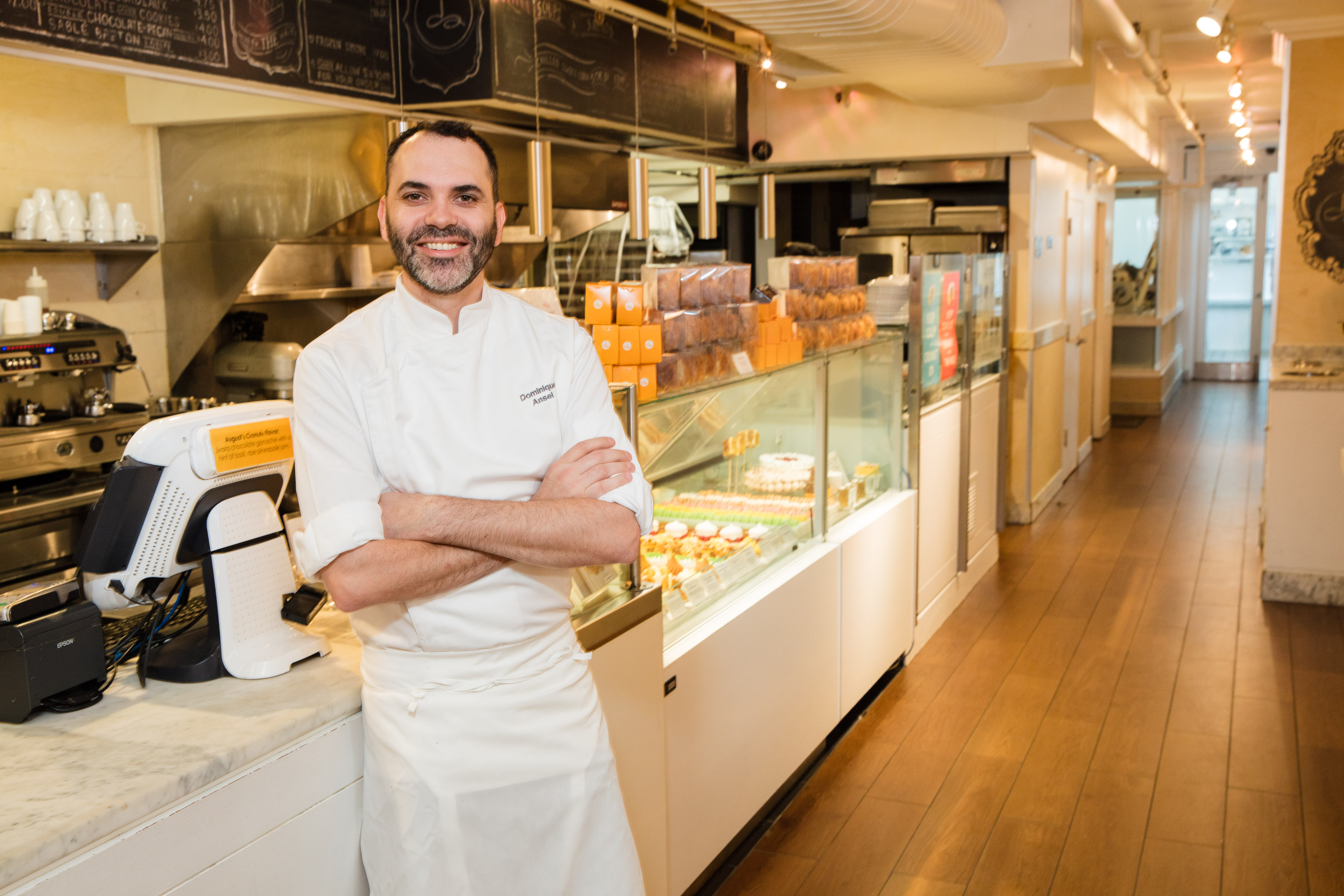 A chef stands with his arms crossed in a bakery.
