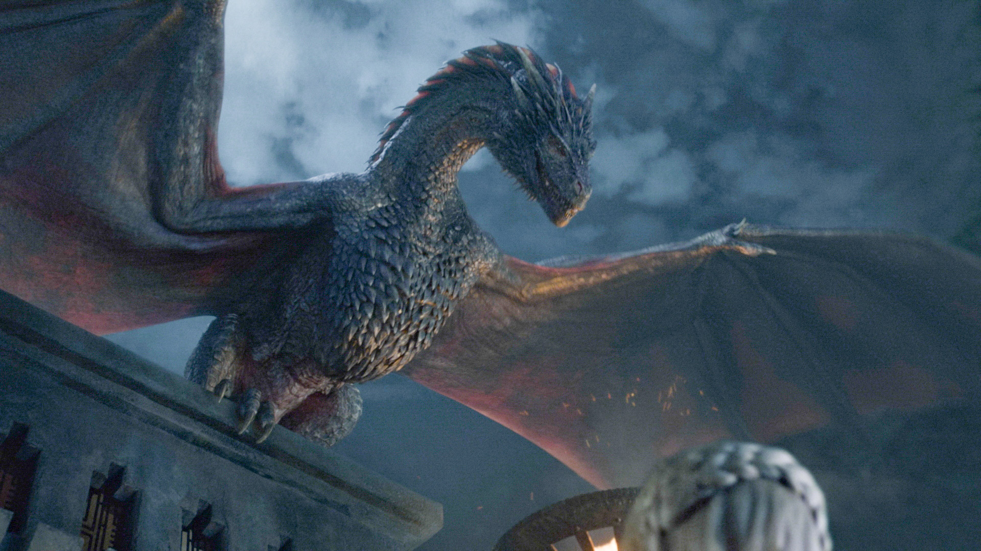 A huge dragon perched on a building with its wings outspread.