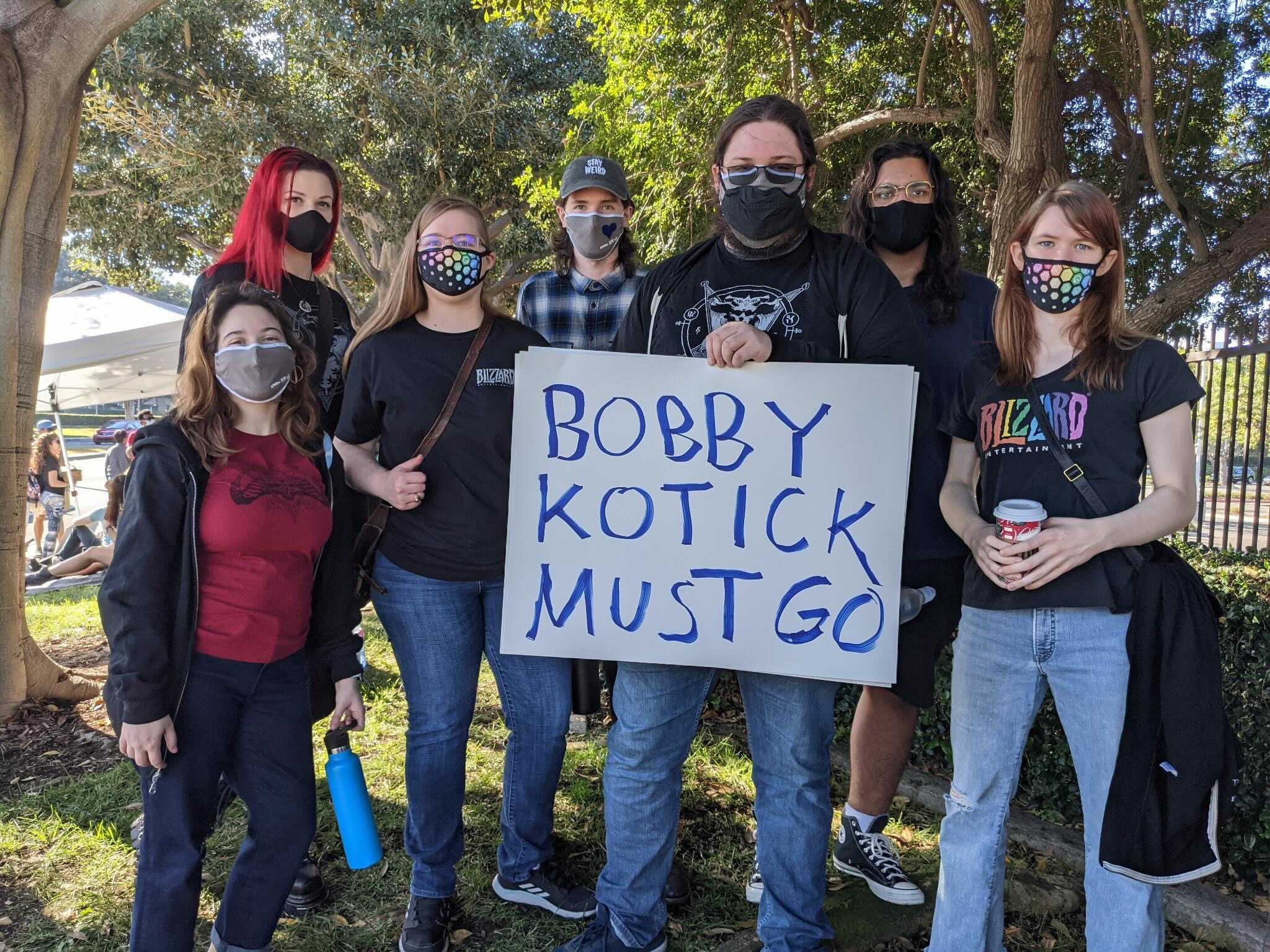 workers/supporters holding a sign that says “bobby kotick must go”