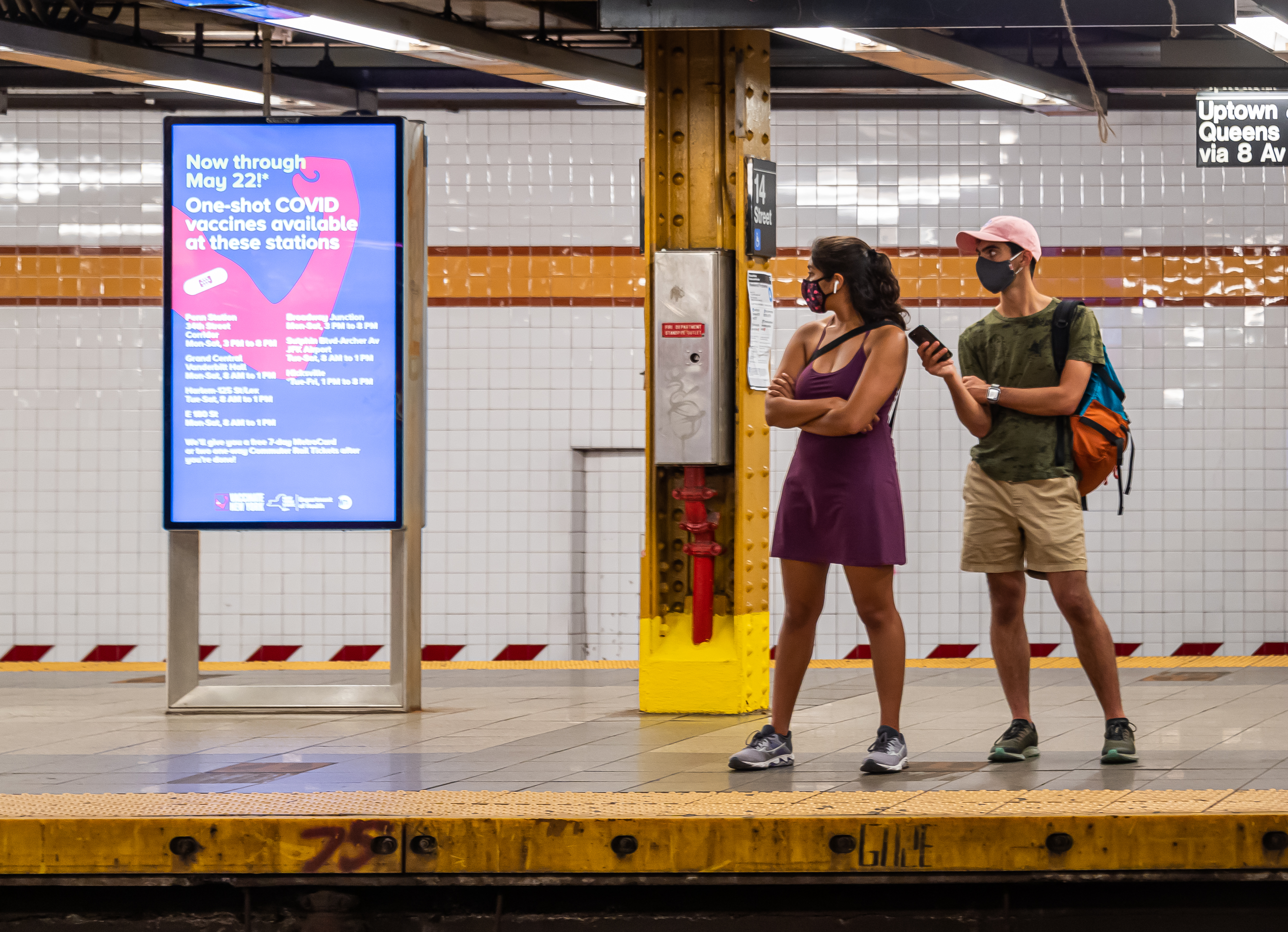 Two people standing on a subway platform.