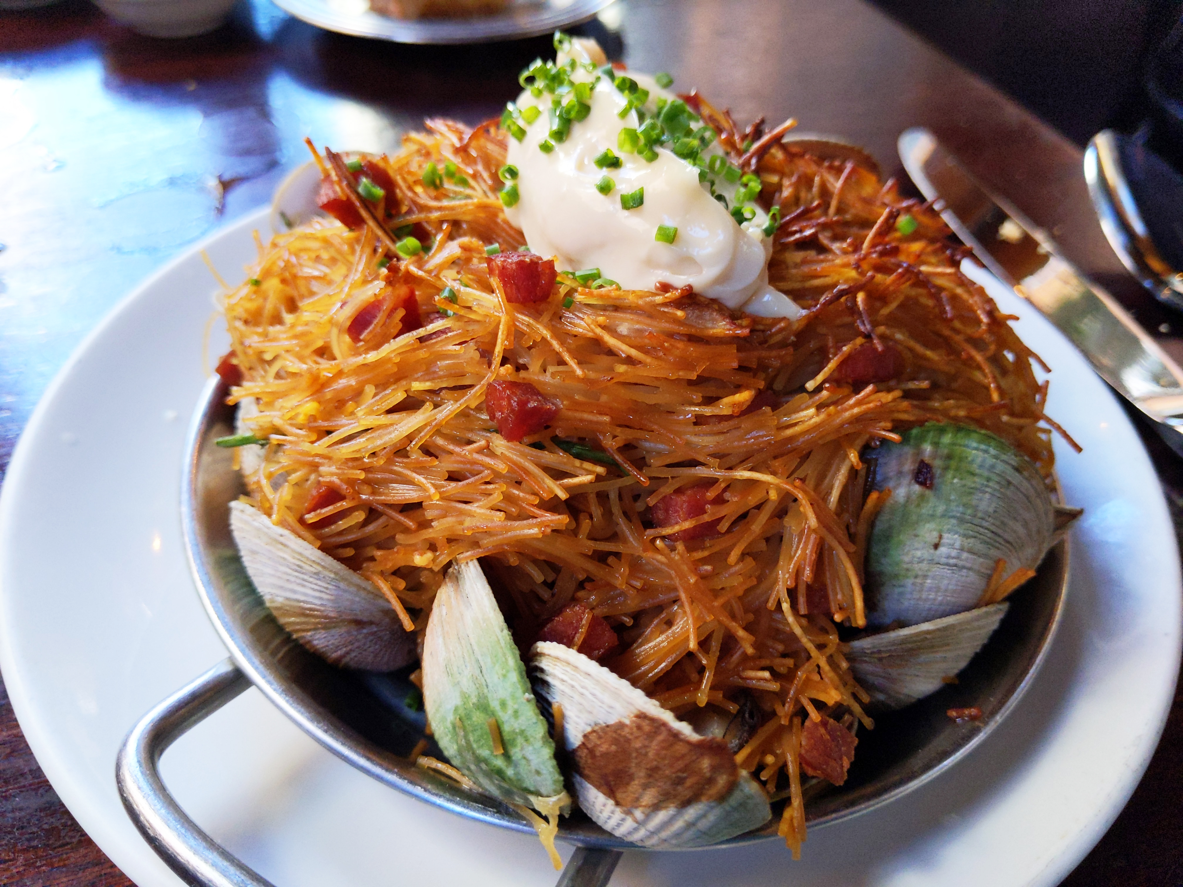 Dark brown toasted noodles interspersed with small in the shell clams, with creamy white dressing in a dollop on top.