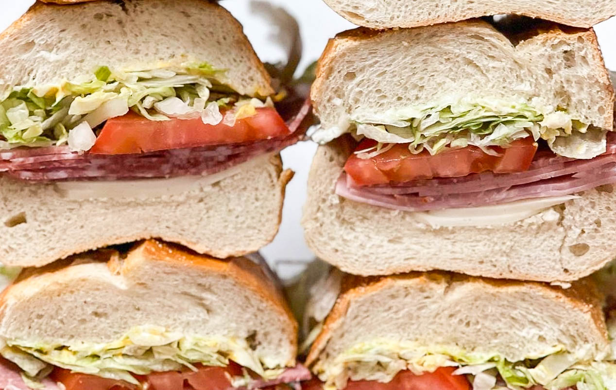 A close up shot of cut sandwiches with Italian ingredients stacked atop one another.