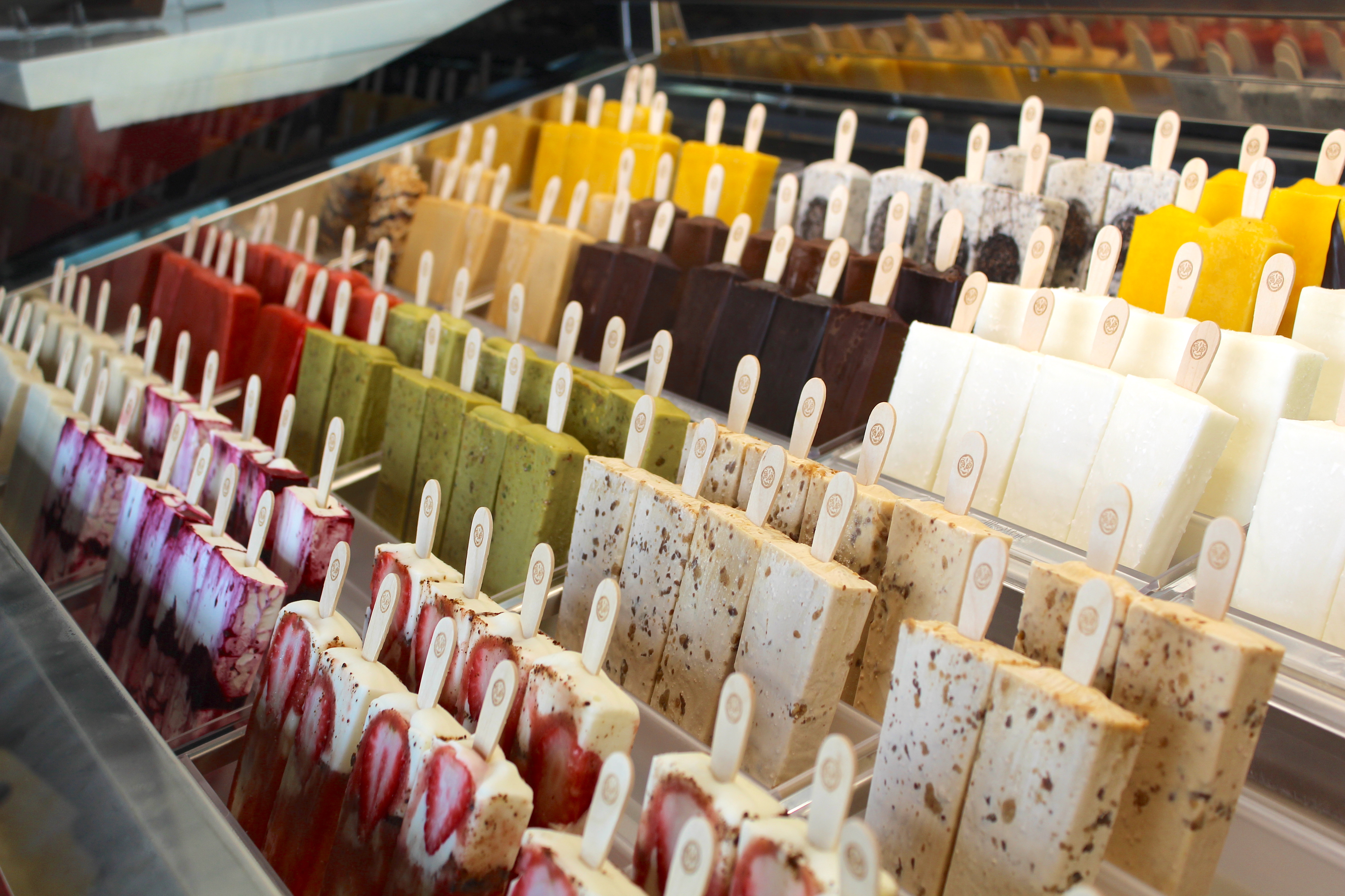 Rows of colorful paletas presented behind a glass case. 