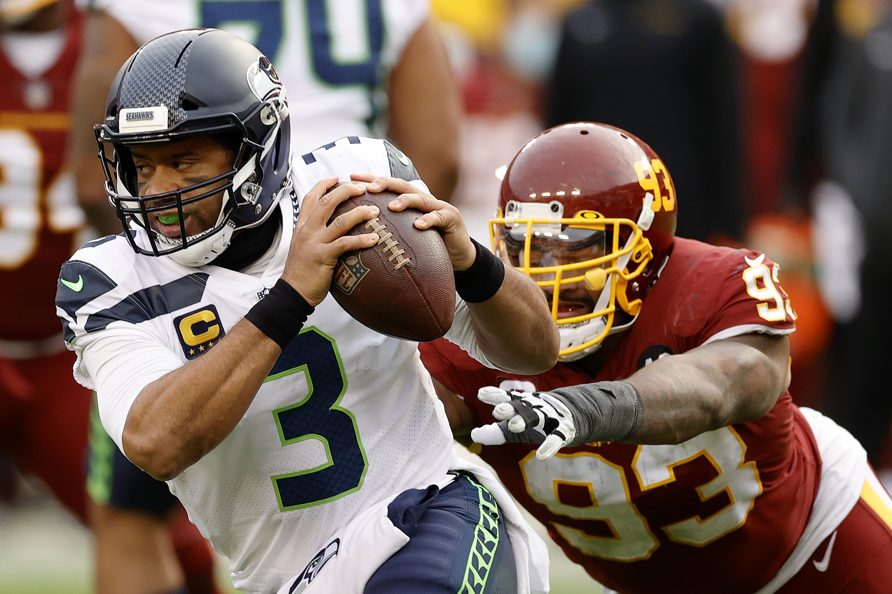 Quarterback Russell Wilson #3 of the Seattle Seahawks eludes the tackle of defensive tackle Jonathan Allen #93 of the Washington Football Team in the second half at FedExField on December 20, 2020 in Landover, Maryland.