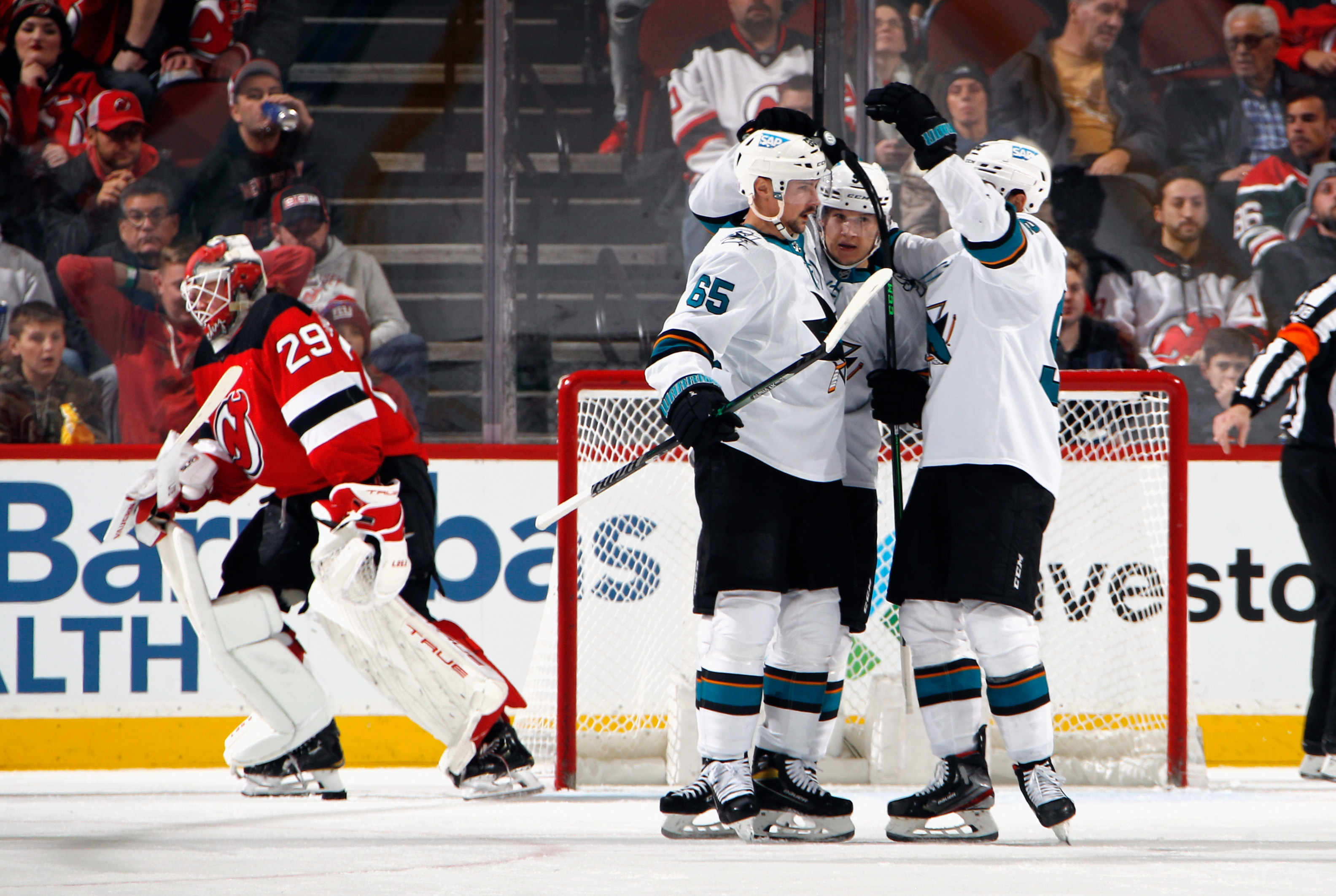 Erik Karlsson #65 of the San Jose Sharks (L) celebrates his second period goal against the New Jersey Devils at the Prudential Center on November 30, 2021 in Newark, New Jersey.