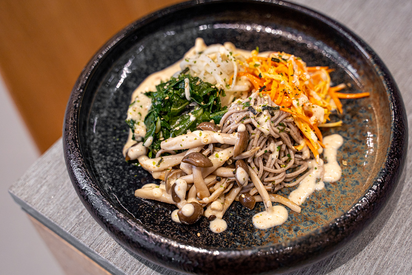 A dish of buckwheat noodles topped with a variety of vegetables.