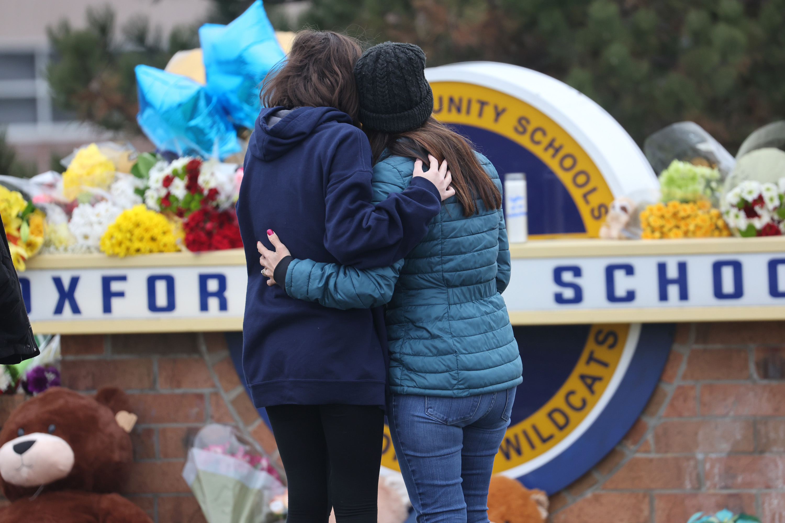 Two women embrace while standing in front of a makeshift memorial outside of Oxford High School in Michigan, where a shooting claimed the lives of four students.