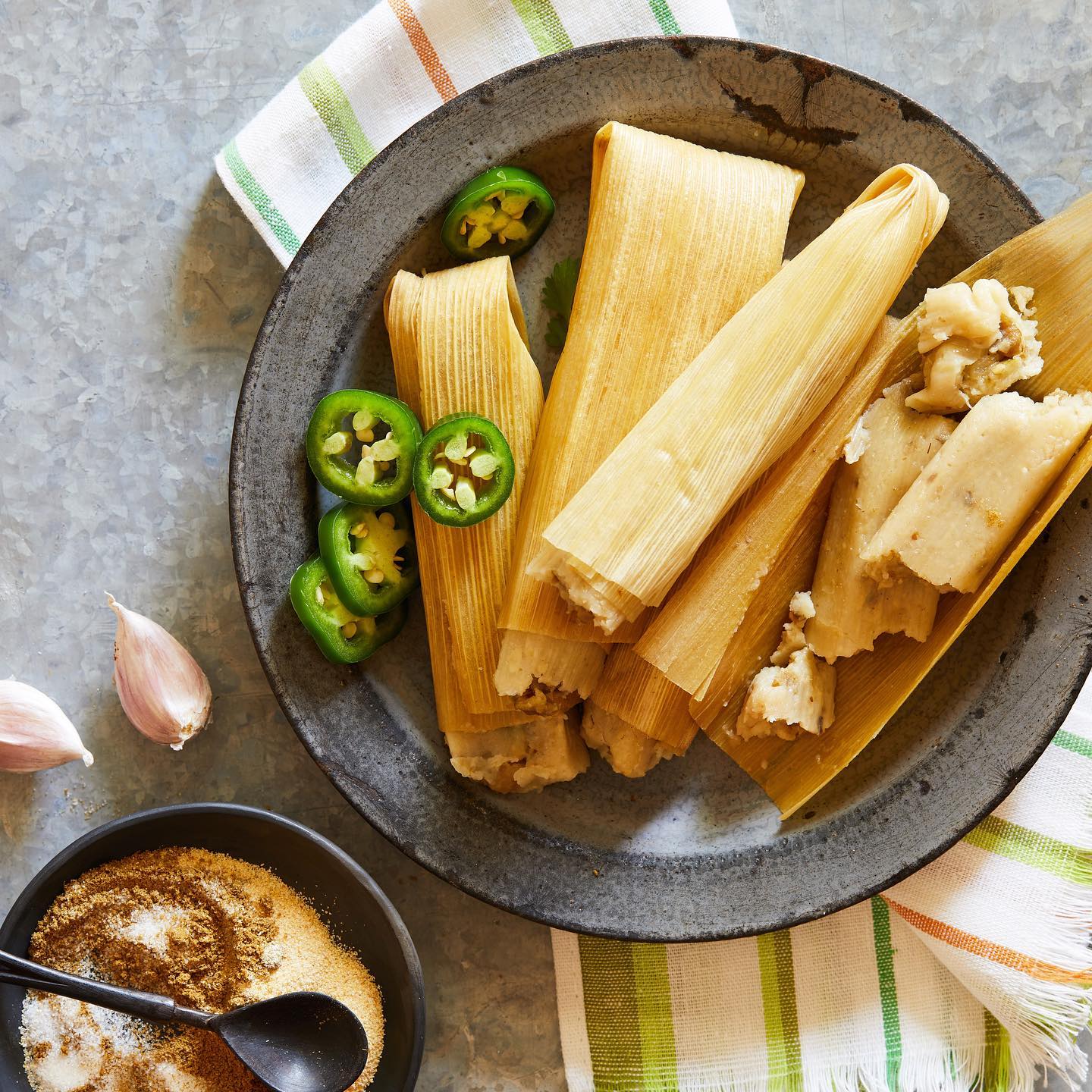 A plate of husked tamales with slices of jalapeños