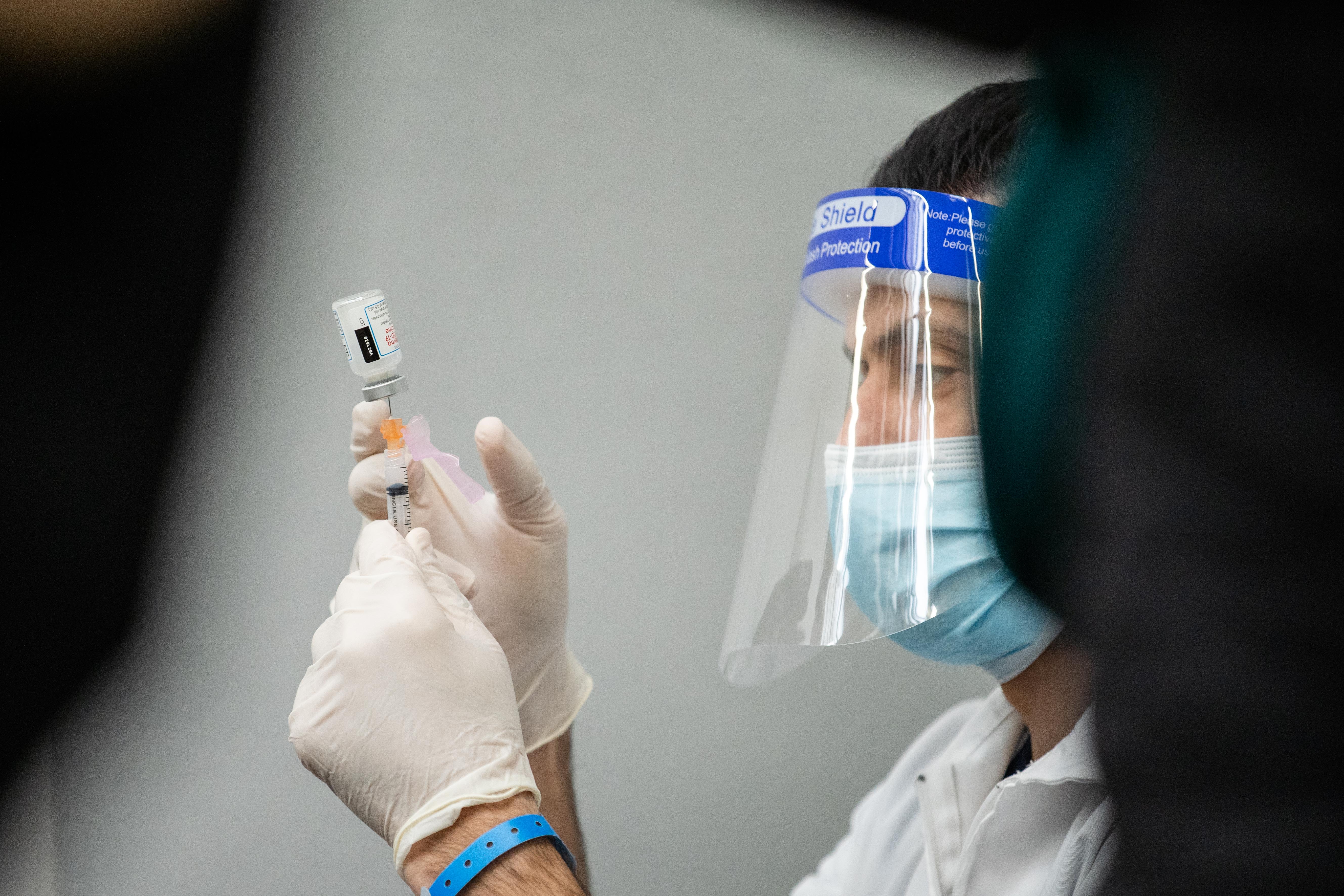 A health care worker prepares a COVID-19 vaccine dose in February on the West Side. Cases are higher in Illinois now than they were 10 months ago.