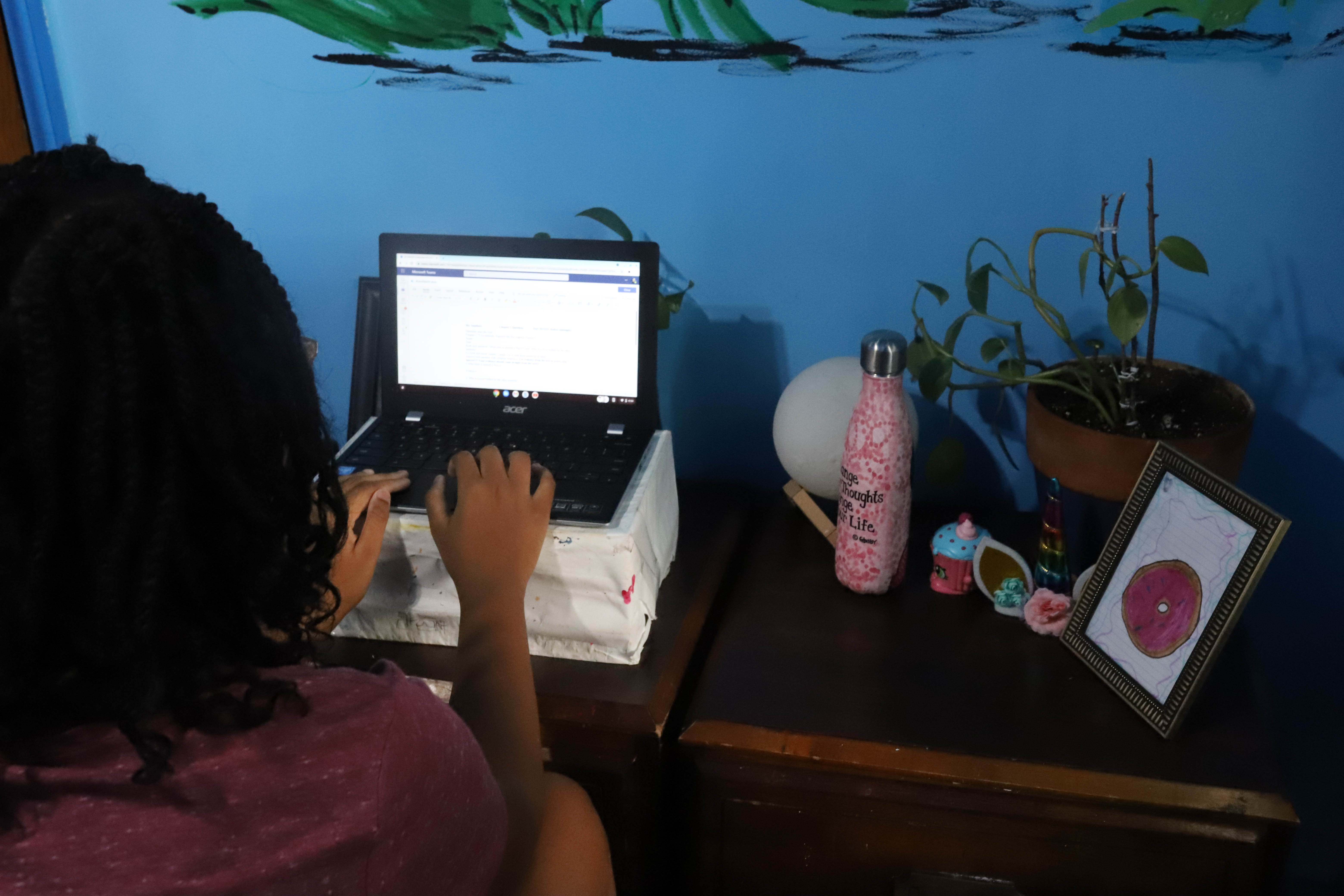 A student works at a laptop in her room.