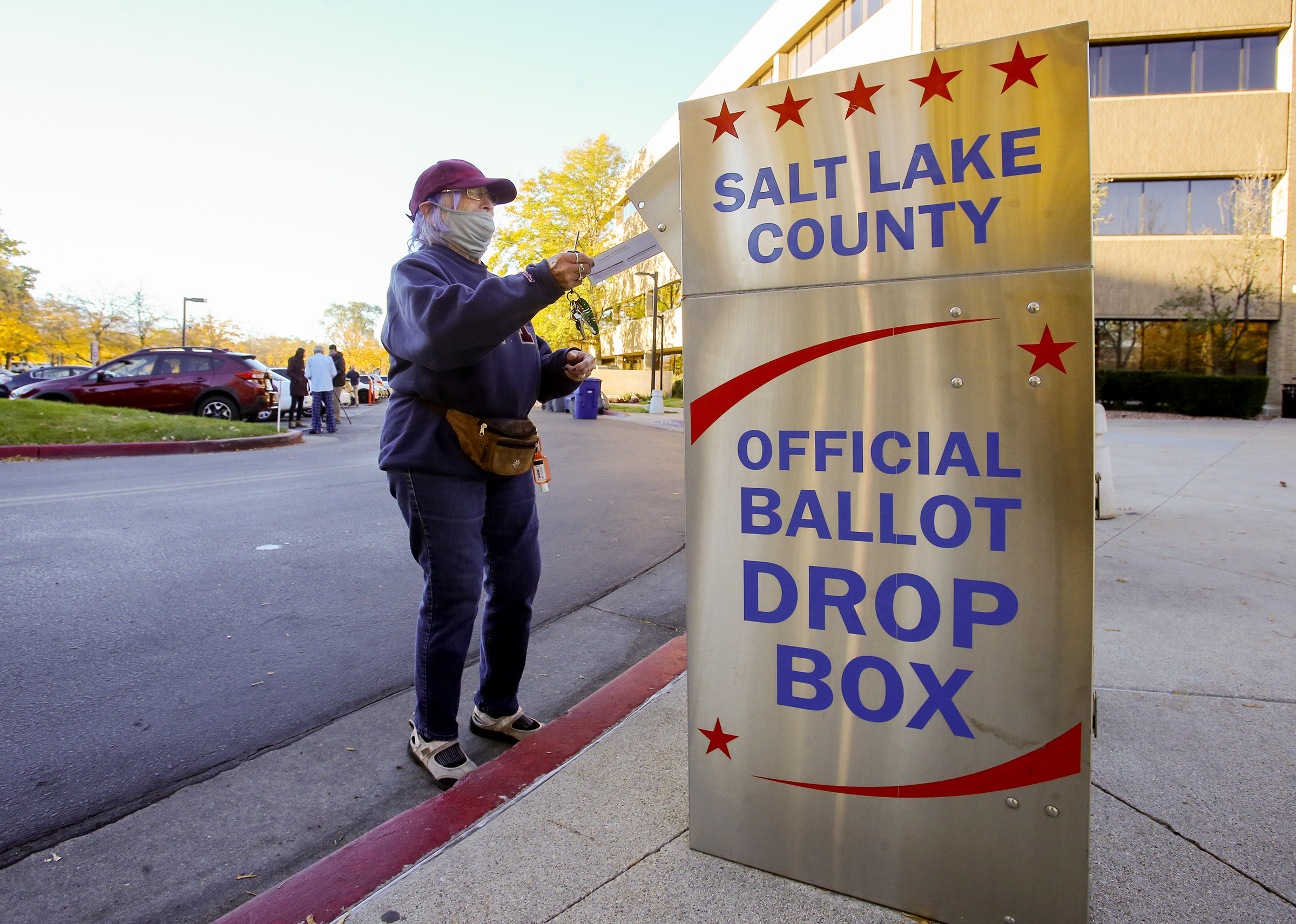 A voter puts a ballot into an official drop box.