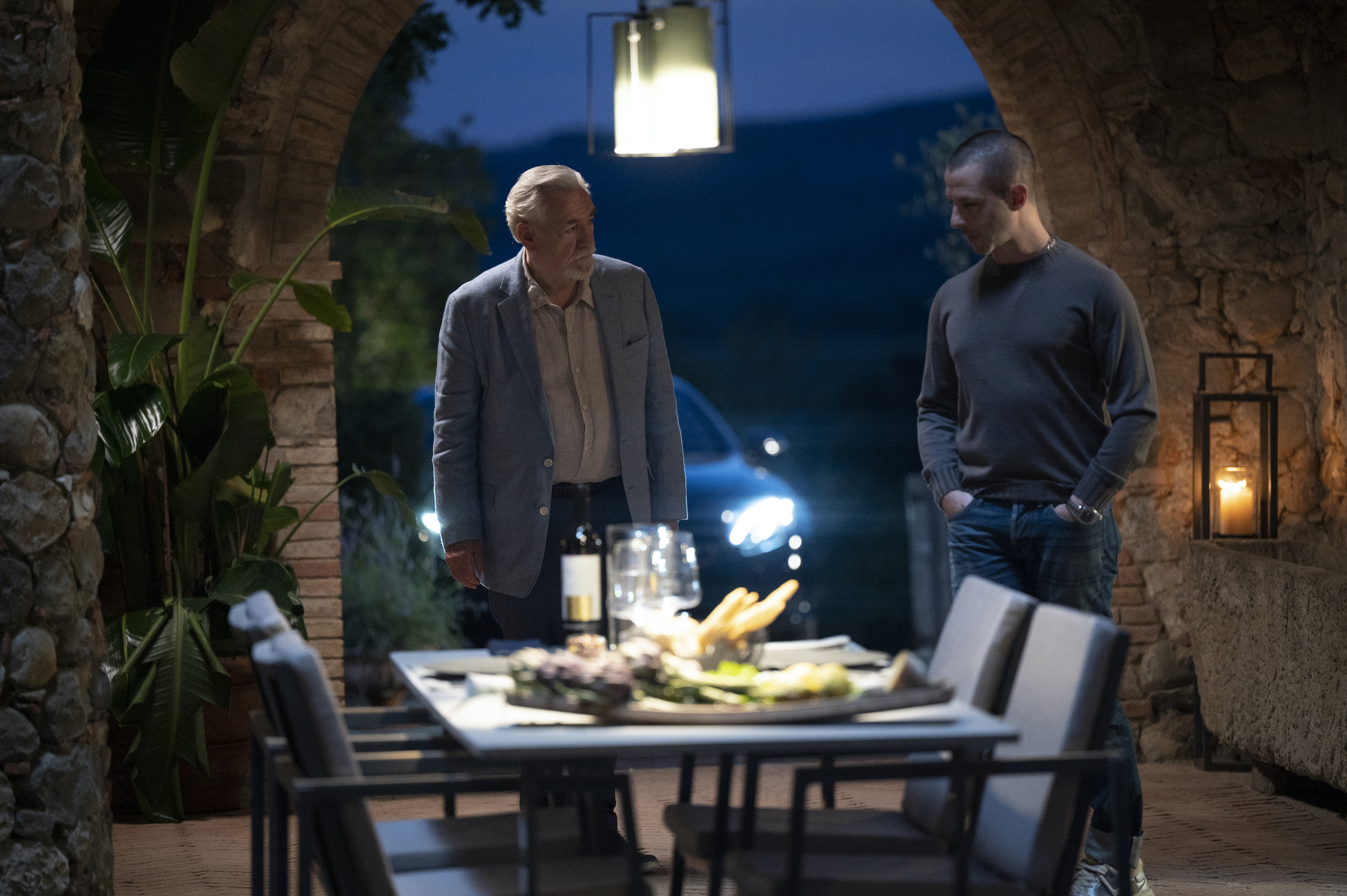 Logan (Brian Cox) and Kendall (Jeremy Strong) gather around a table in the Italian night. 