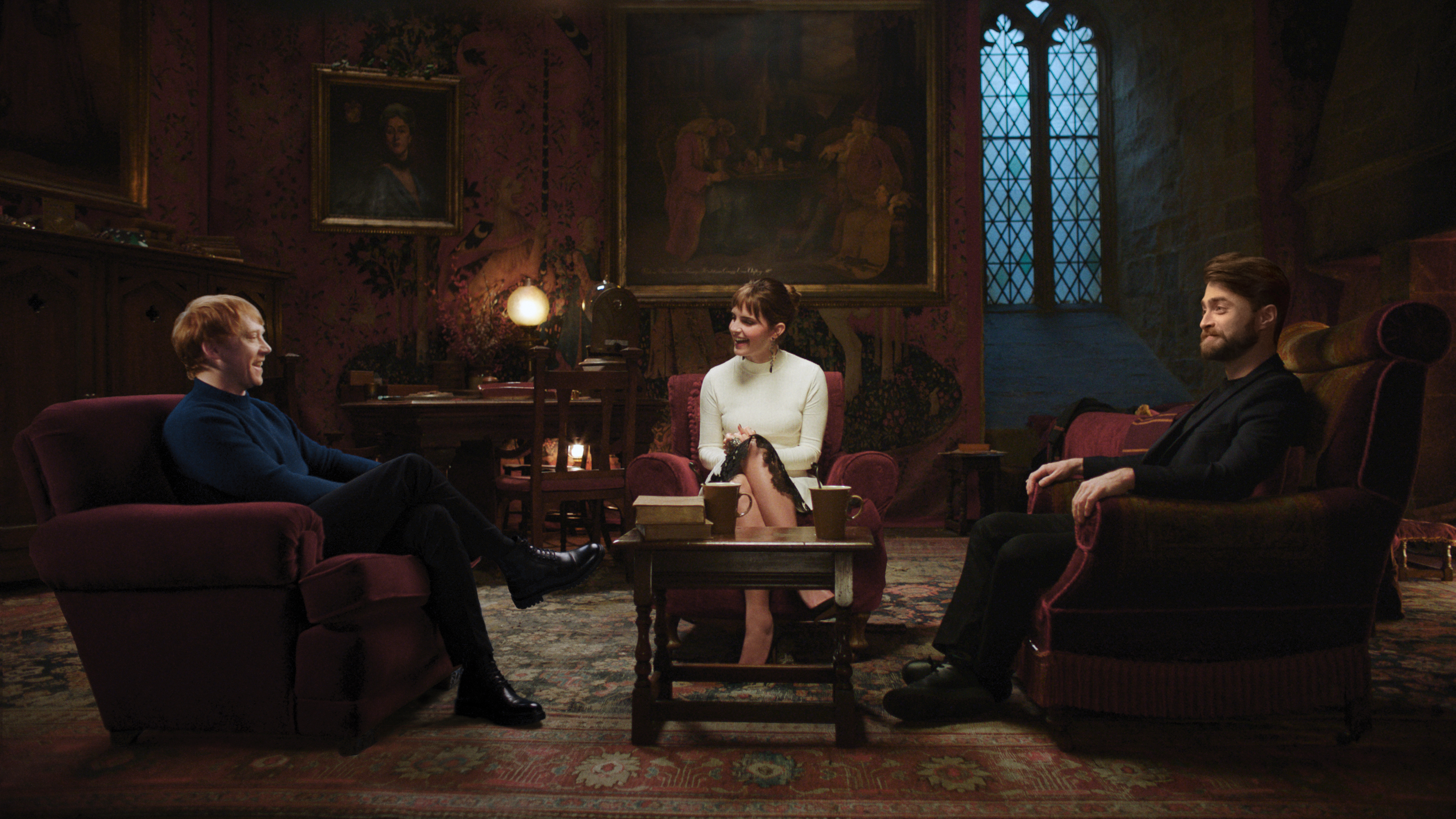 rupert grint, emma watson, and daniel radcliffe all sitting in the gryffindor common room 
